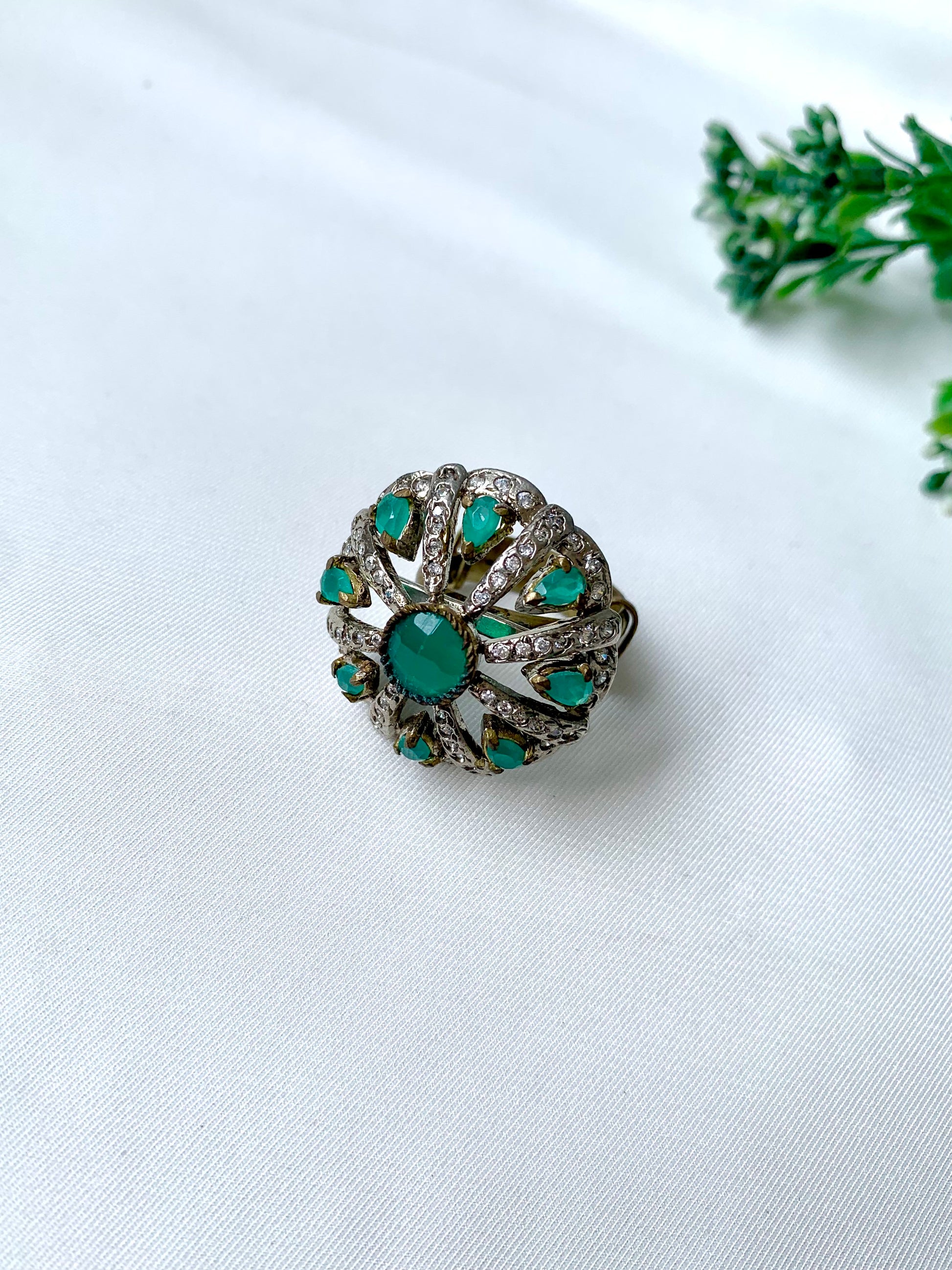 Close-up of Selene Bloom Ring with Semi-Precious Emerald stones and American Diamonds in antique Victorian rhodium finish, displayed on white fabric