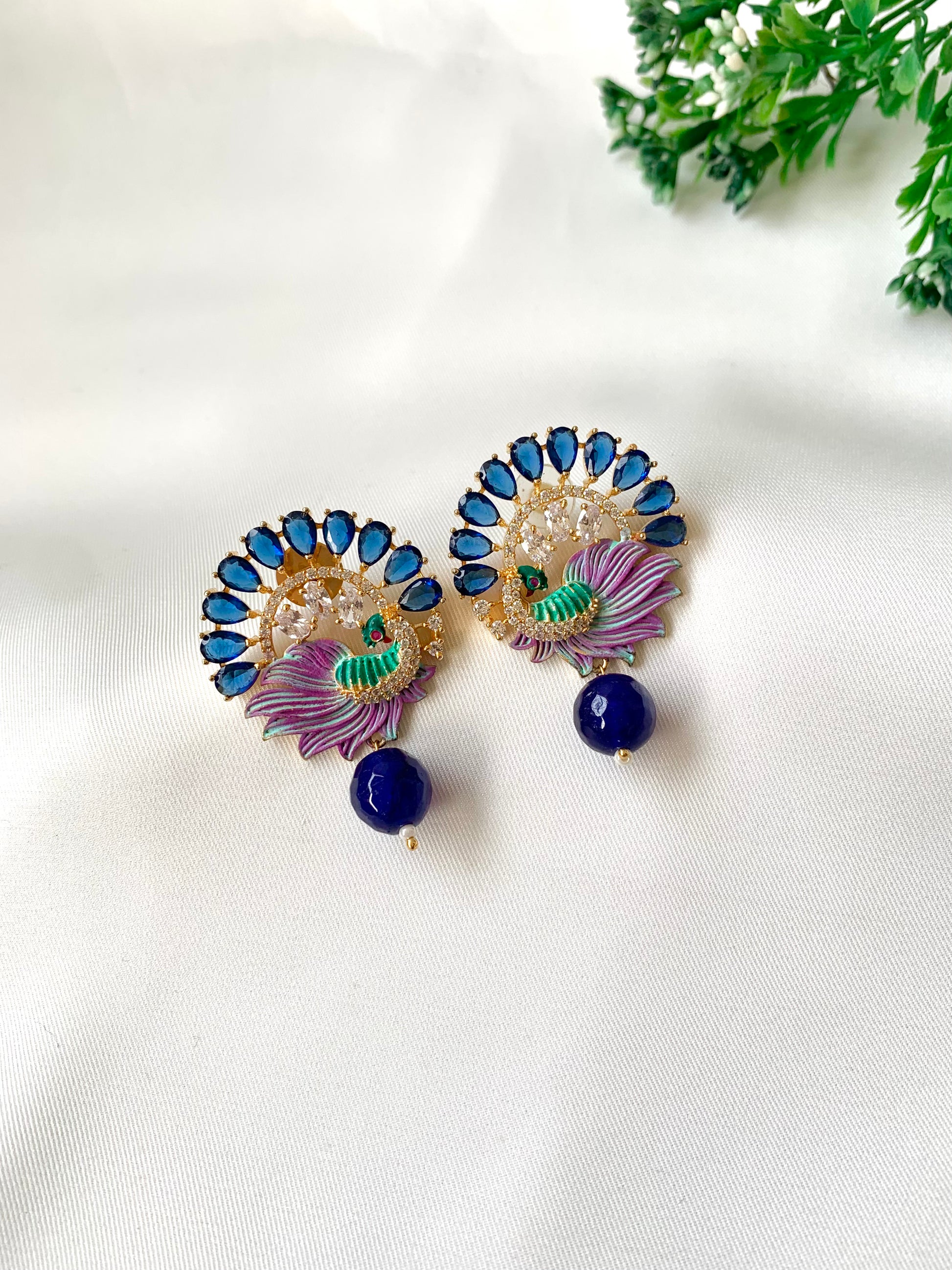 Pair of decorative earrings with blue and purple stones on a white background