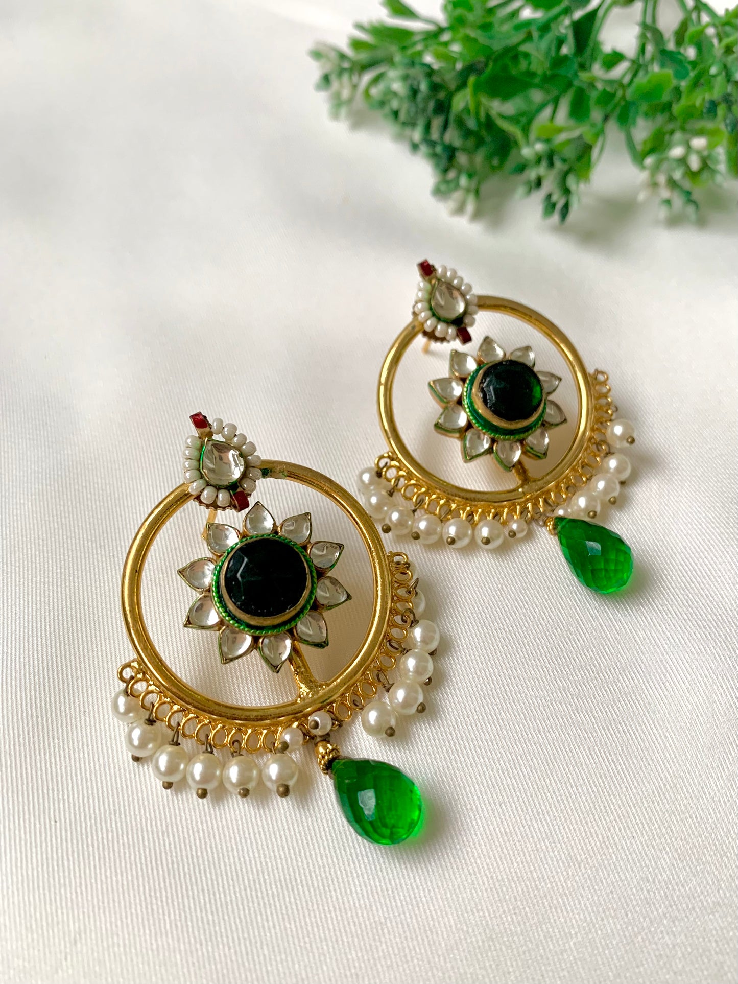 22kt Gold Plated handcrafted earrings with Pachi Kundan, semi-precious emerald centre, pearl detailing, and emerald teardrop accents displayed on a white fabric background.