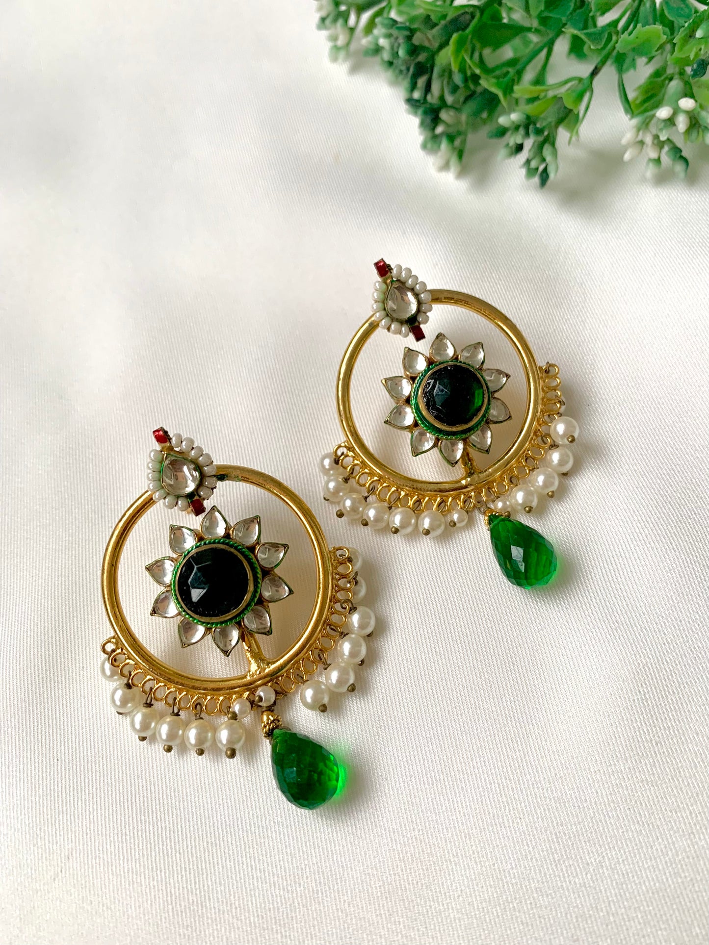 22kt Gold Plated handcrafted earrings with Pachi Kundan, semi-precious emerald centre, pearl detailing, and emerald teardrop accents displayed on a white fabric background.