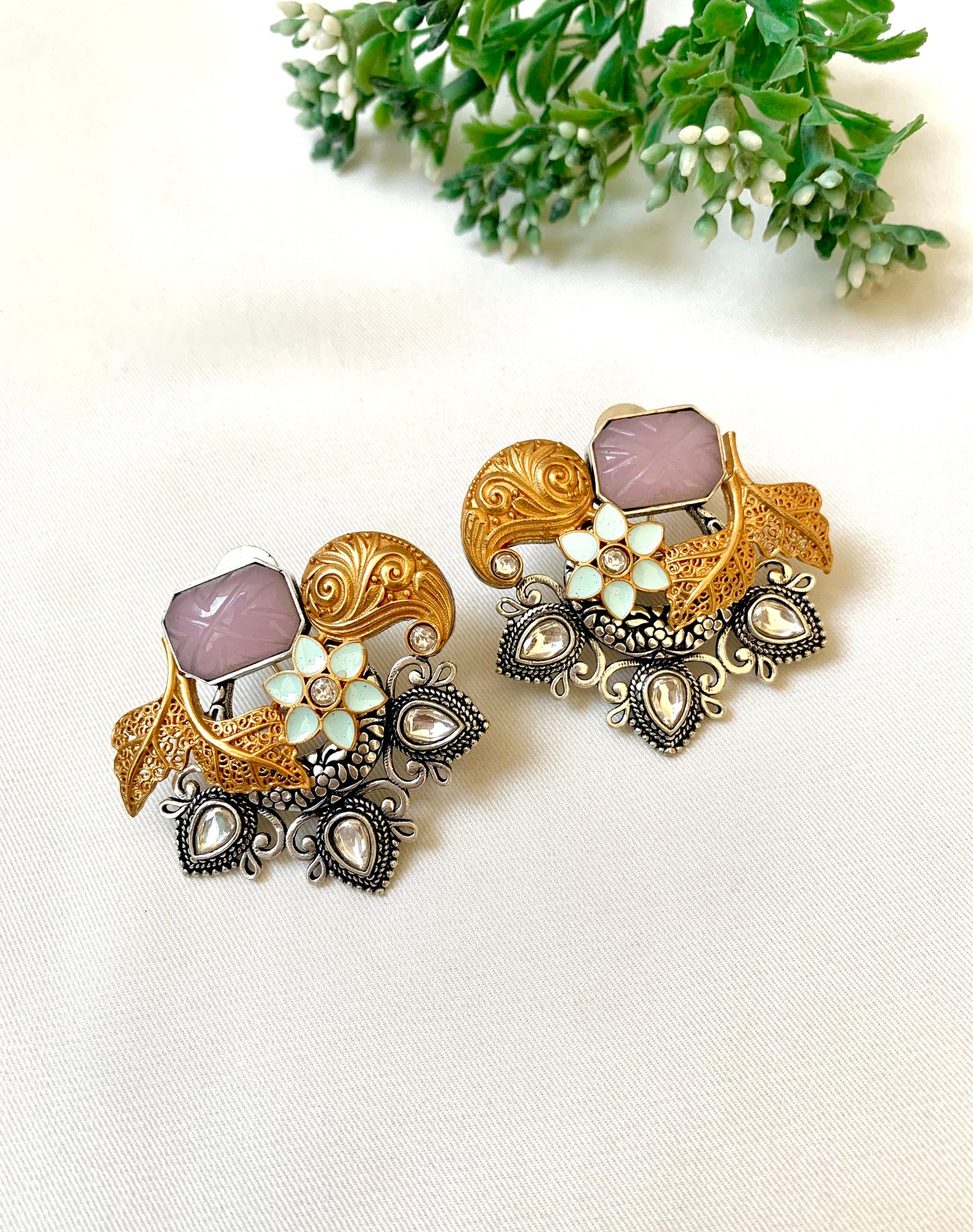 Ornate gold and silver earrings with pink stones on a white background