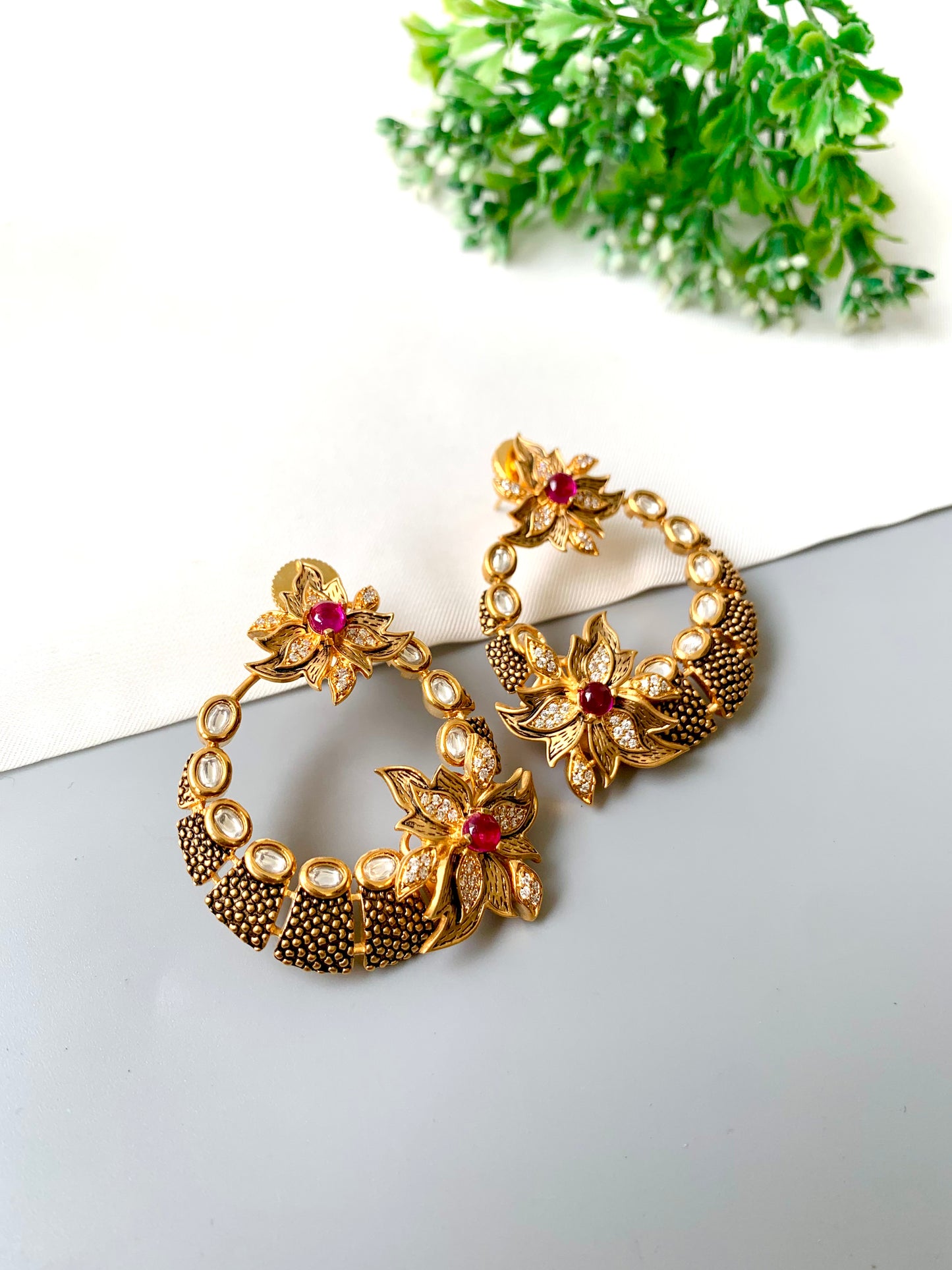 Close-up of floral Kundan hoops with ruby centres and textured detailing in 22k gold finish — Zamal Jewels