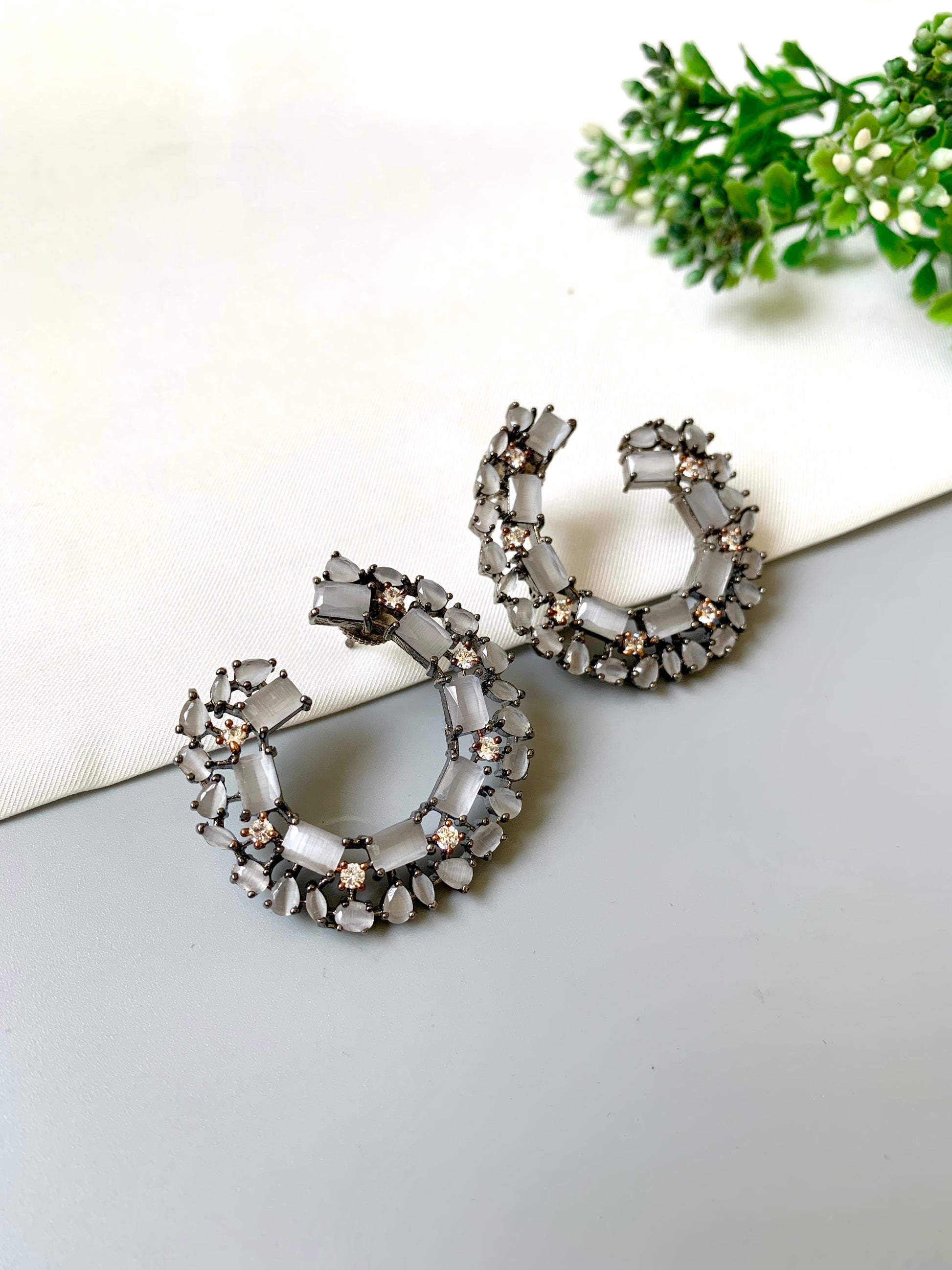 Close-up of Arden statement earrings with American Diamonds and onyx stones set in a sleek rhodium hoop frame
