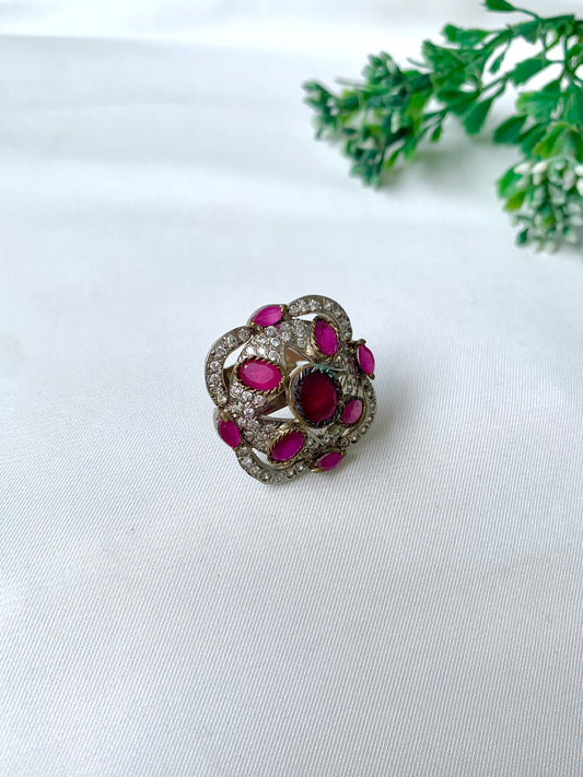 Handcrafted rhodium-plated Victorian-style ring with American Diamonds and semi-precious ruby stones on a white fabric backdrop