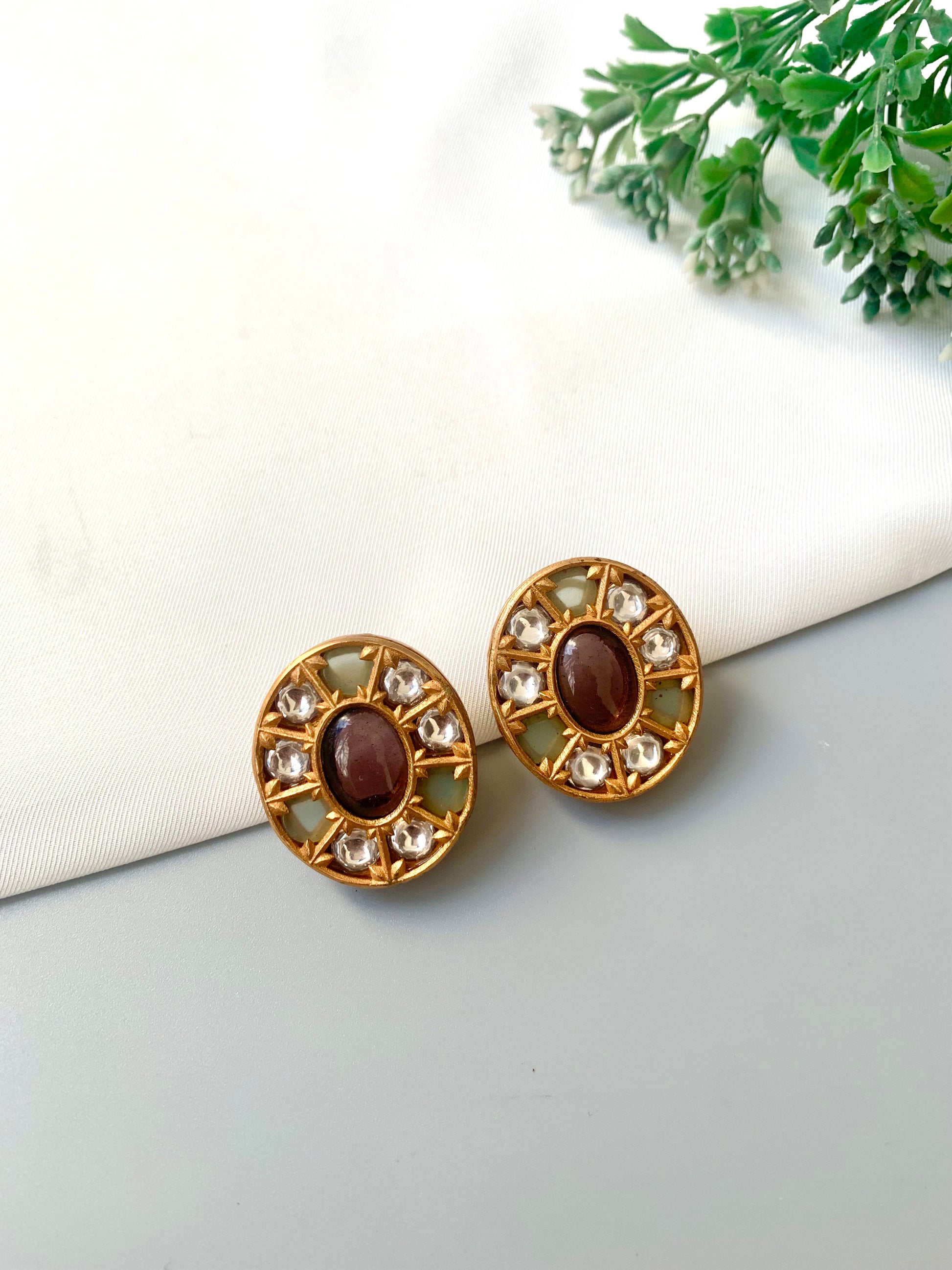 Top-angle image of Asmita Amethyst earrings featuring oval amethyst center and antique gold finish.