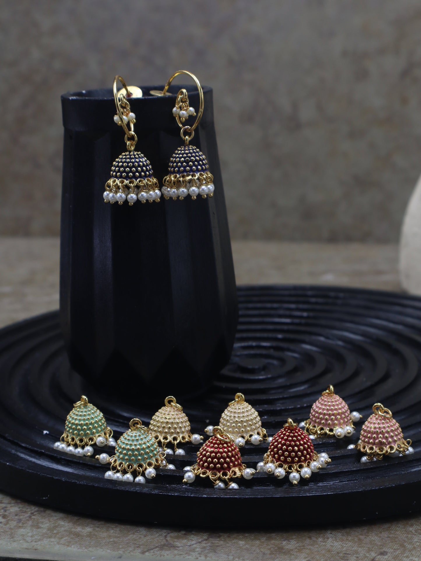 Zamal Jewels Baila Jhumki Set displayed on wooden logs with 5 interchangeable Meena domes and hoop earrings