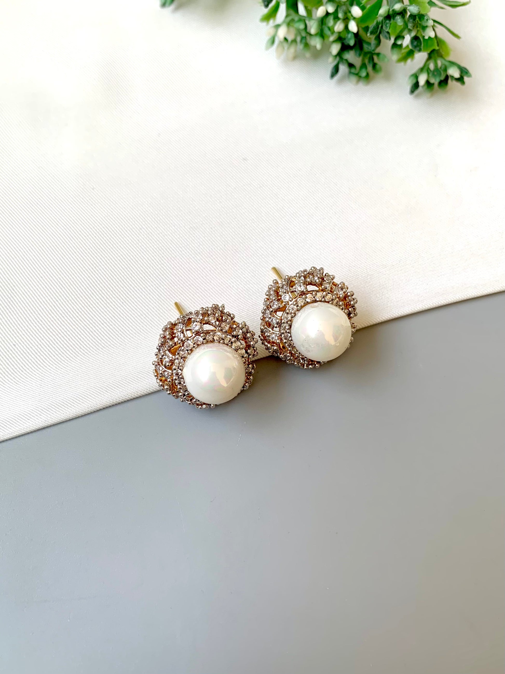 Pair of pearl earrings with gold accents on a light gray surface.