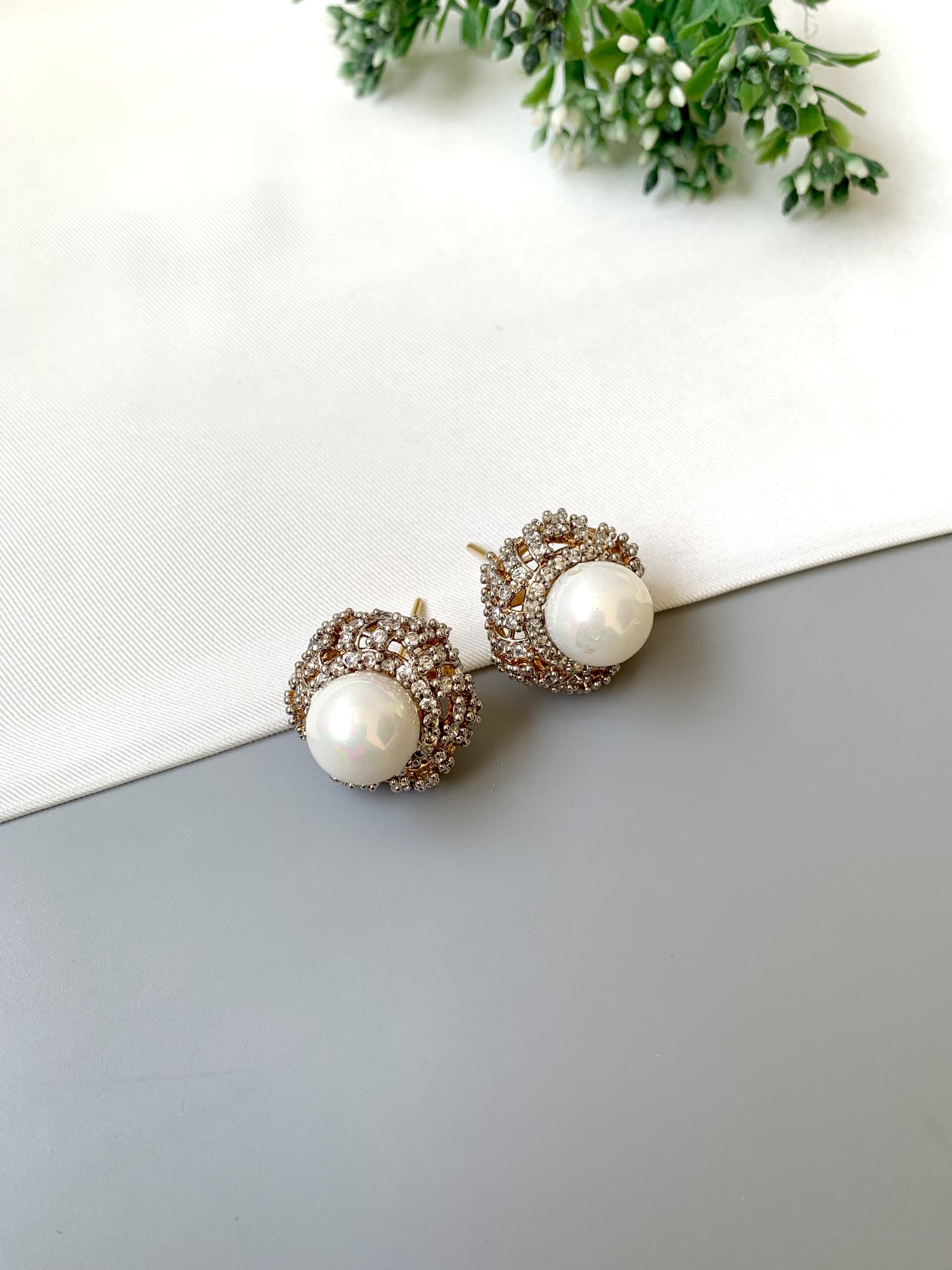 Pair of pearl earrings with gold accents on a white and gray surface.