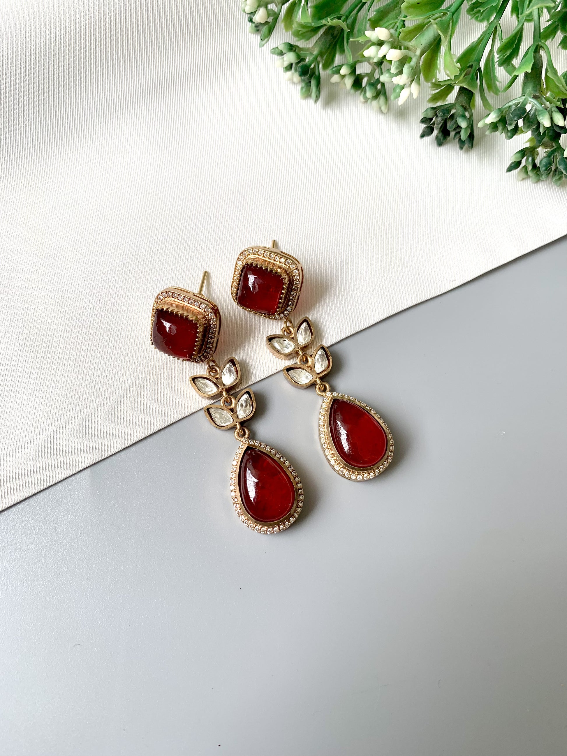 Close-up of Elayra earrings with semi-precious ruby stones and 22kt gold finish, accented with Kundan and American Diamonds