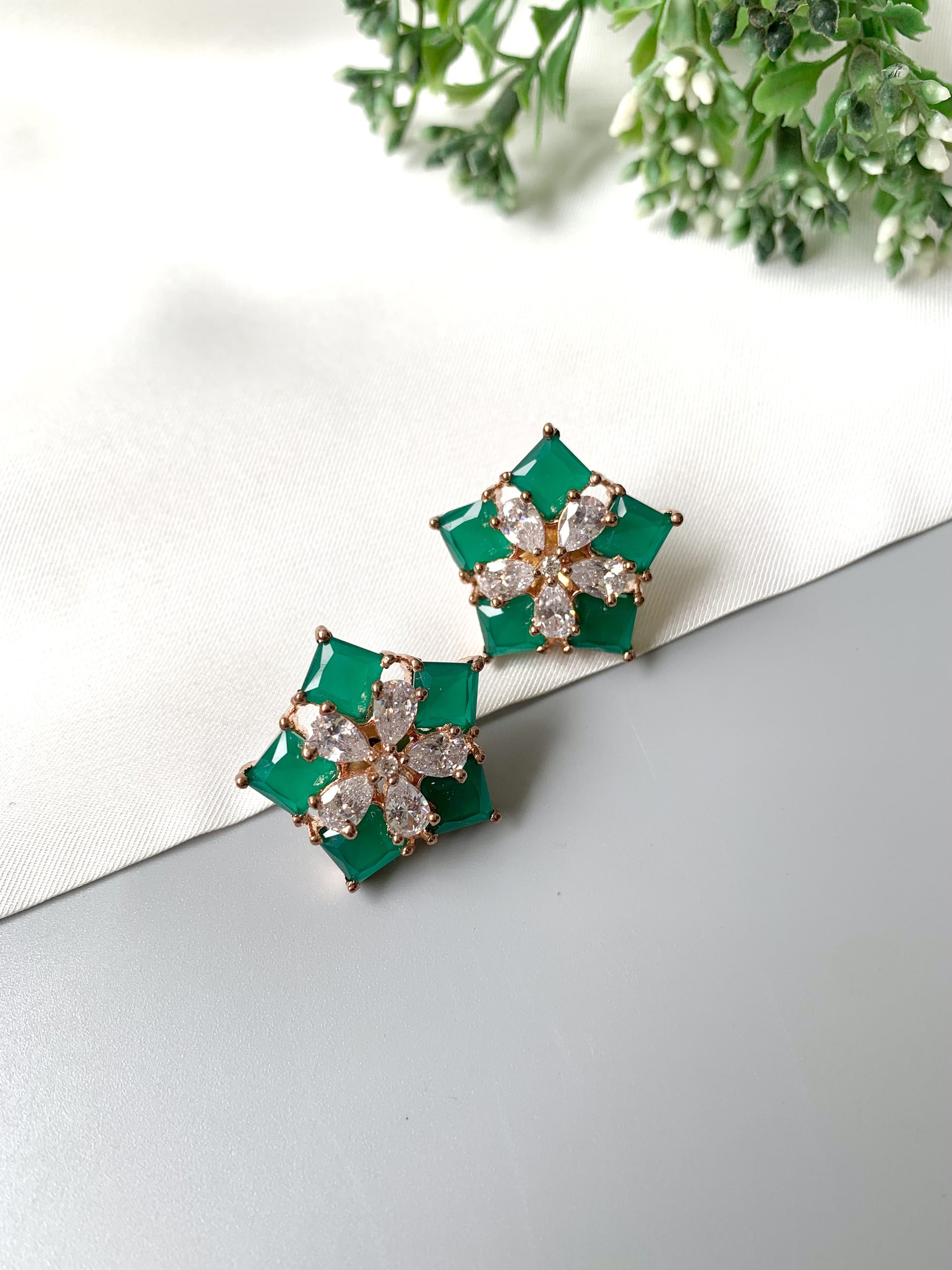 Close-up of floral motif emerald studs in oxidized rose gold