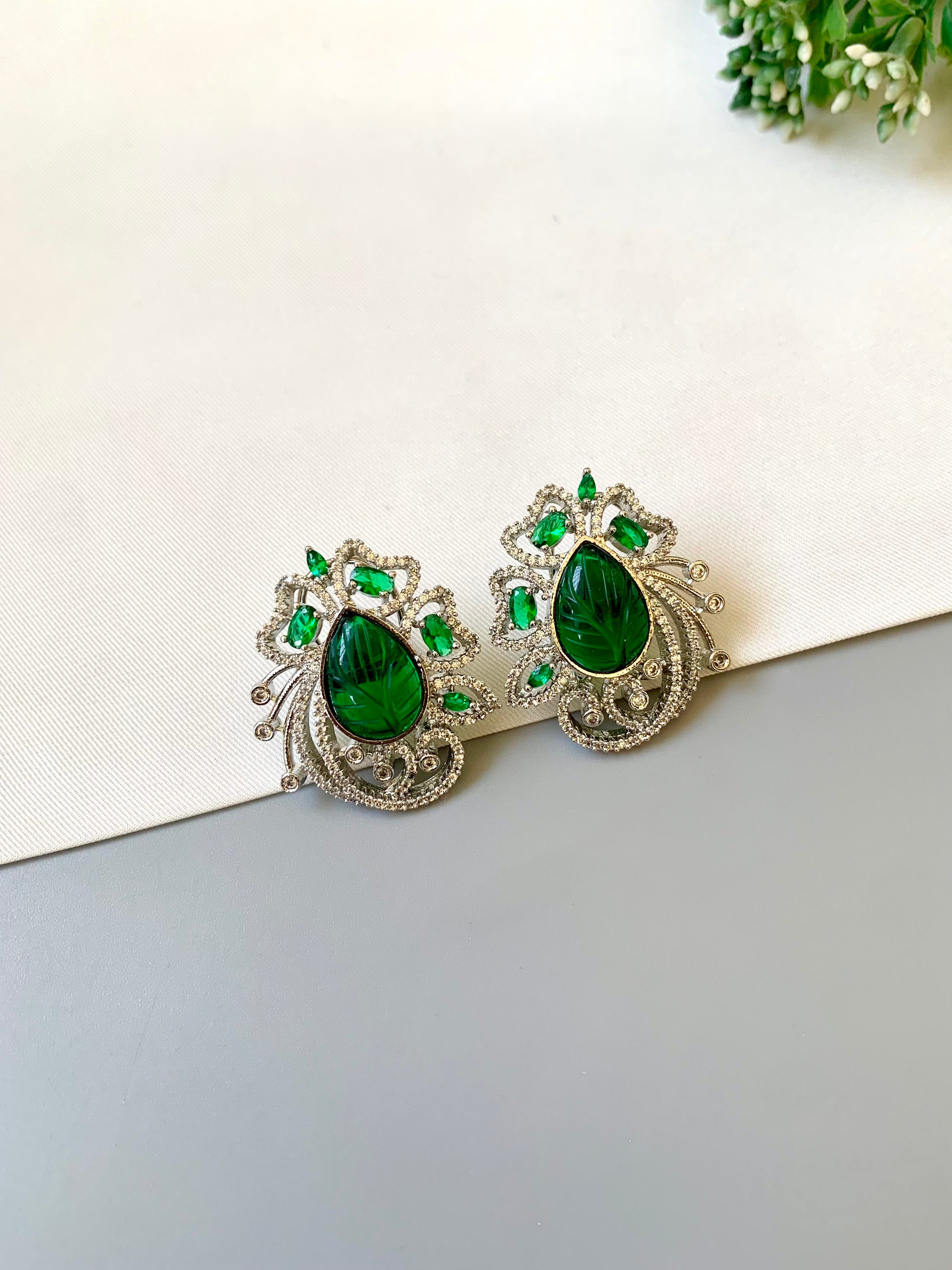 Hand crafted Ena Emerald studs in rhodium plating with diamond finish, featuring American Diamonds, hand carved Emerald stones