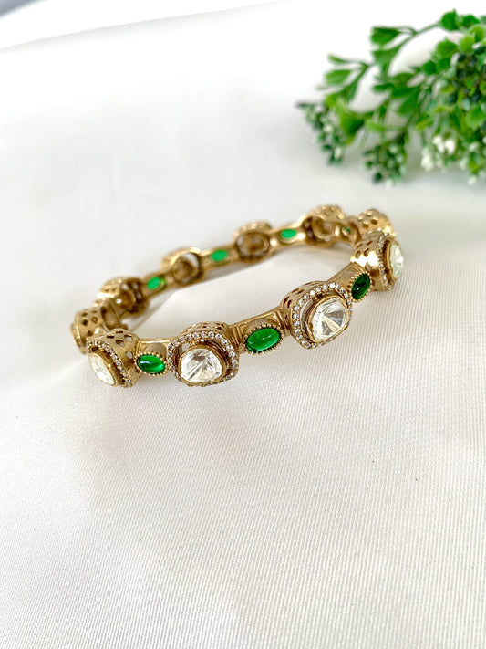 22kt Gold Plated Jahanara Emerald Bangle with Moissanite Kundan, American Diamonds & Semi-Precious Emerald stones on a white fabric base