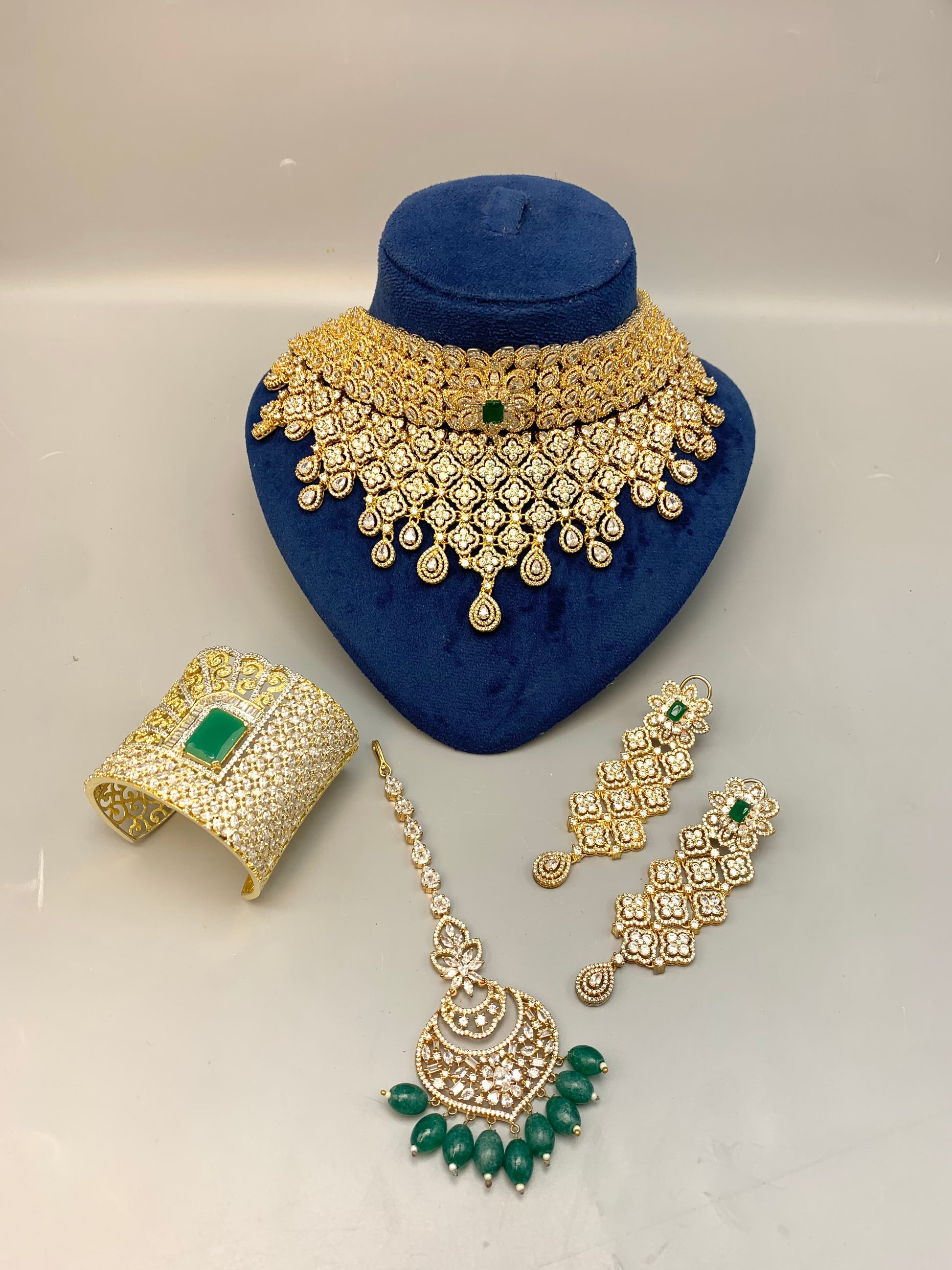 Jamna handcrafted 22kt gold plated bridal set with American Diamonds, semi-precious Emeralds, choker, earrings, tikka and hand cuff