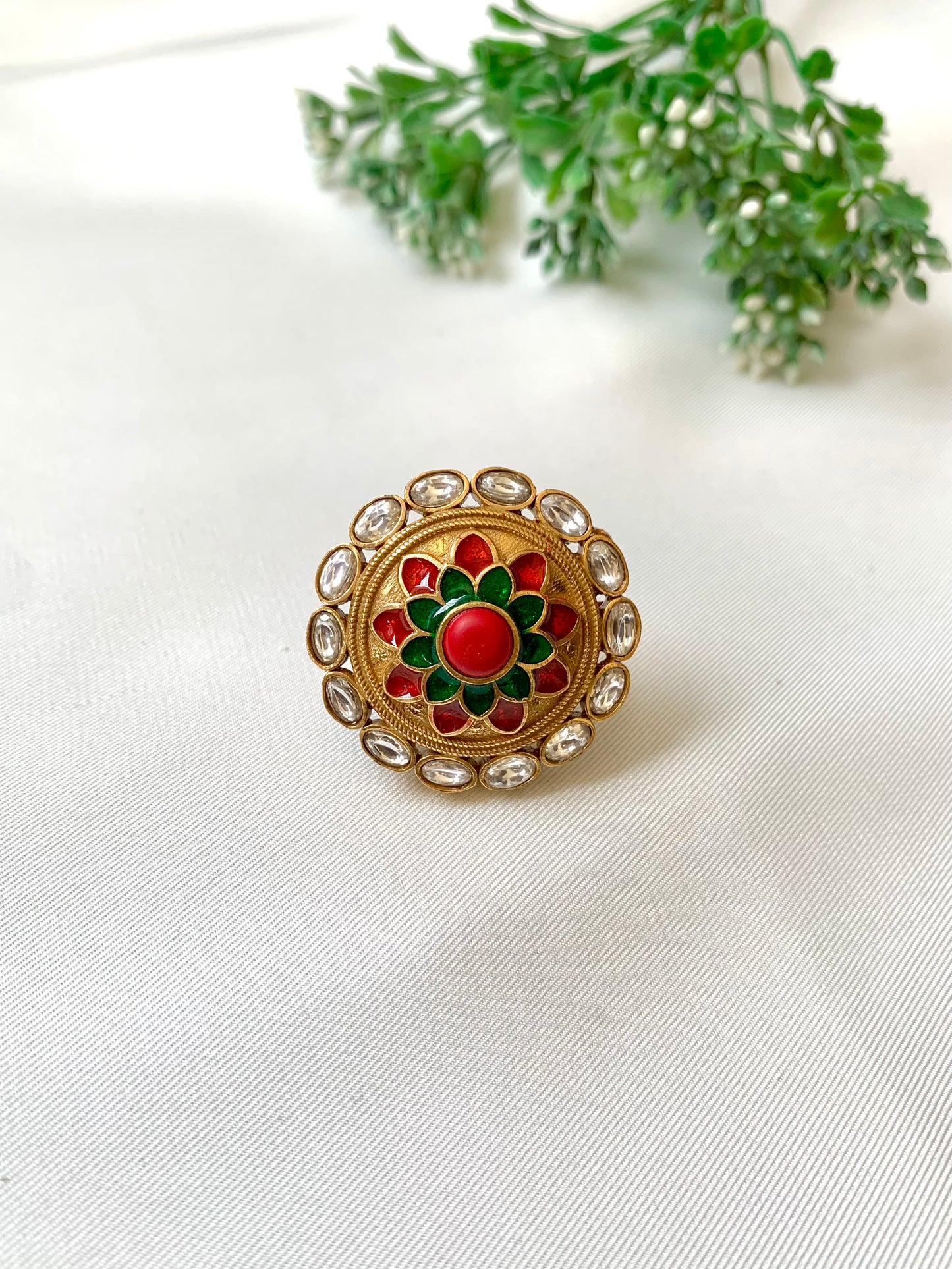 Decorative brooch with red and green center on a white fabric background