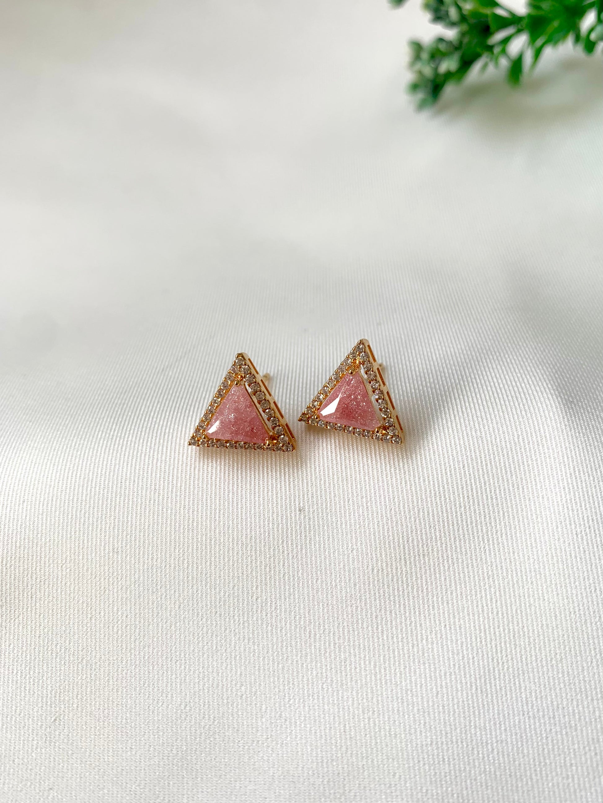 Triangle-shaped pink earrings on a white background