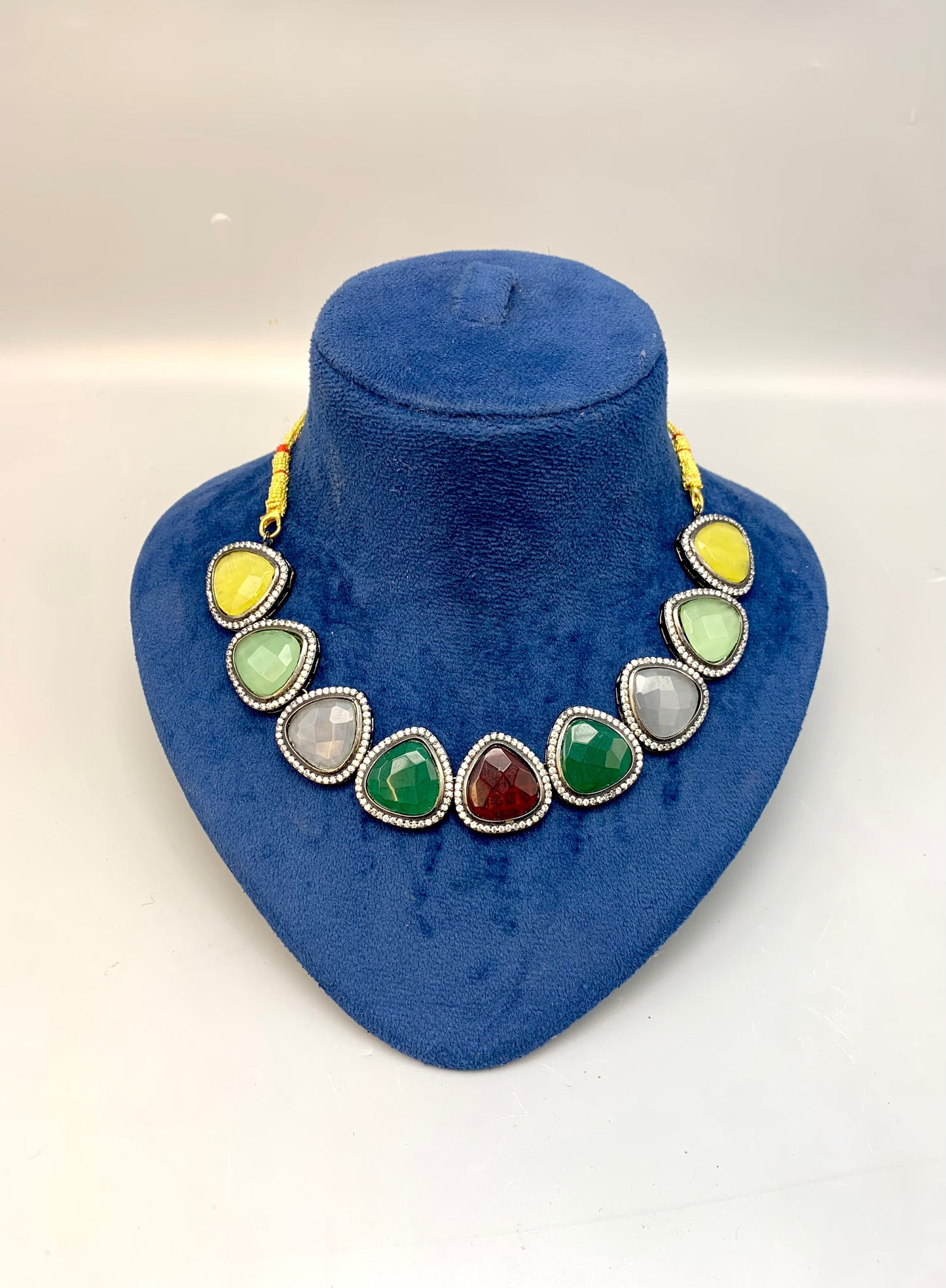 Necklace with multicolored stones on a blue velvet stand