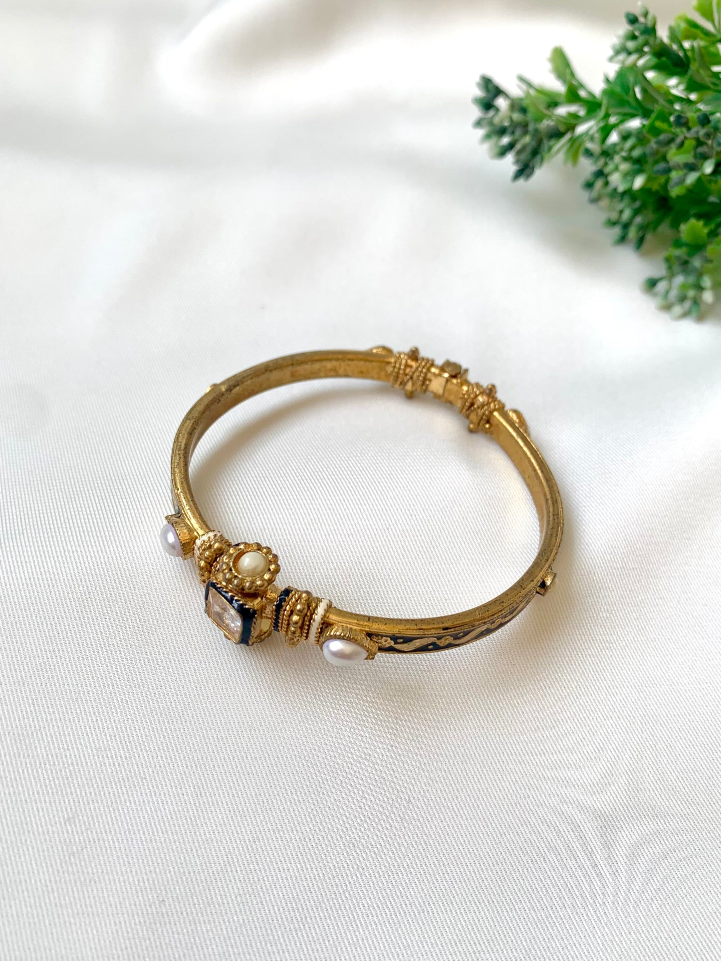 Gold bracelet with decorative elements on a white fabric background