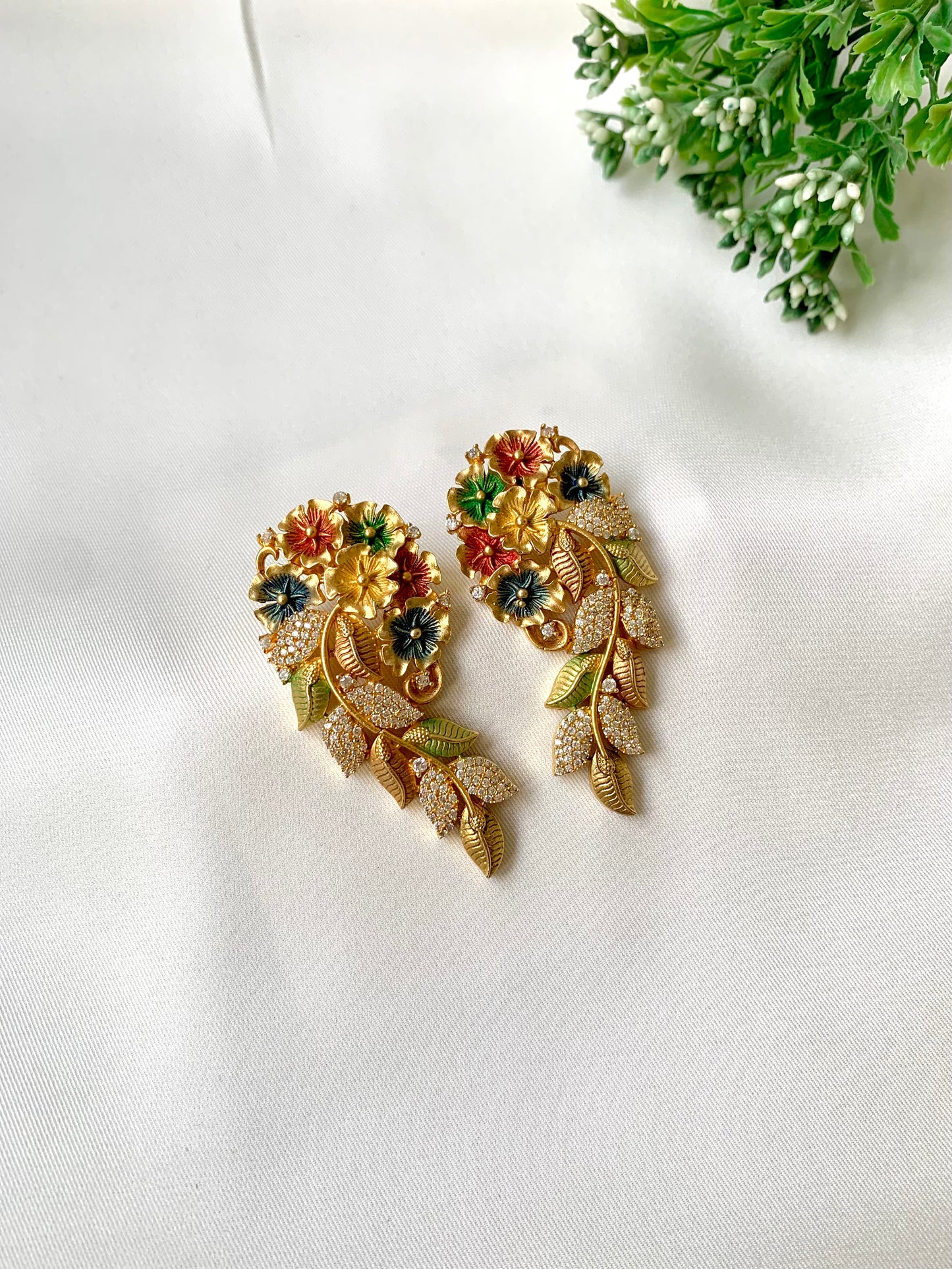 Gold earrings with floral designs on a white background