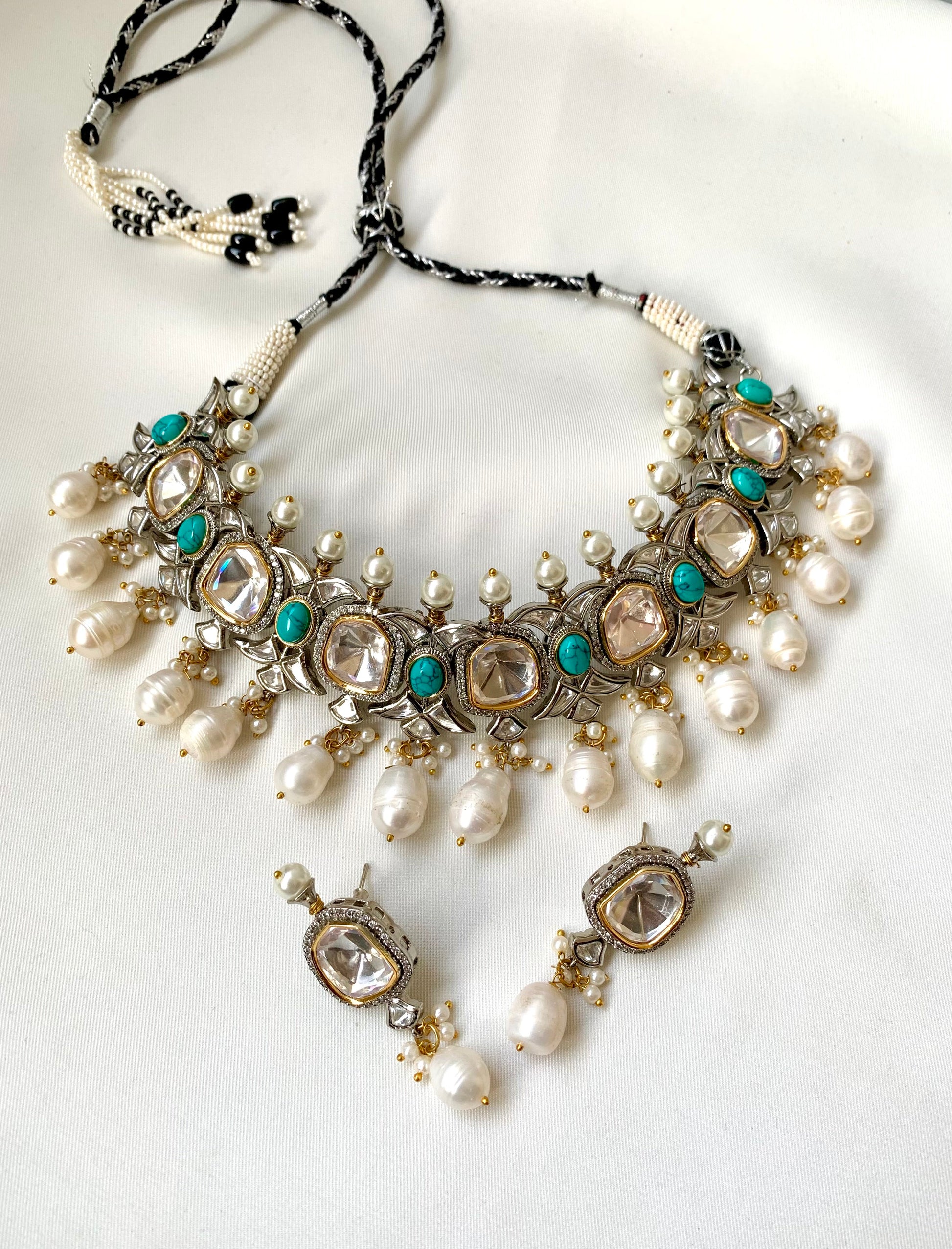 Ornate necklace with pearls and turquoise stones on a white background