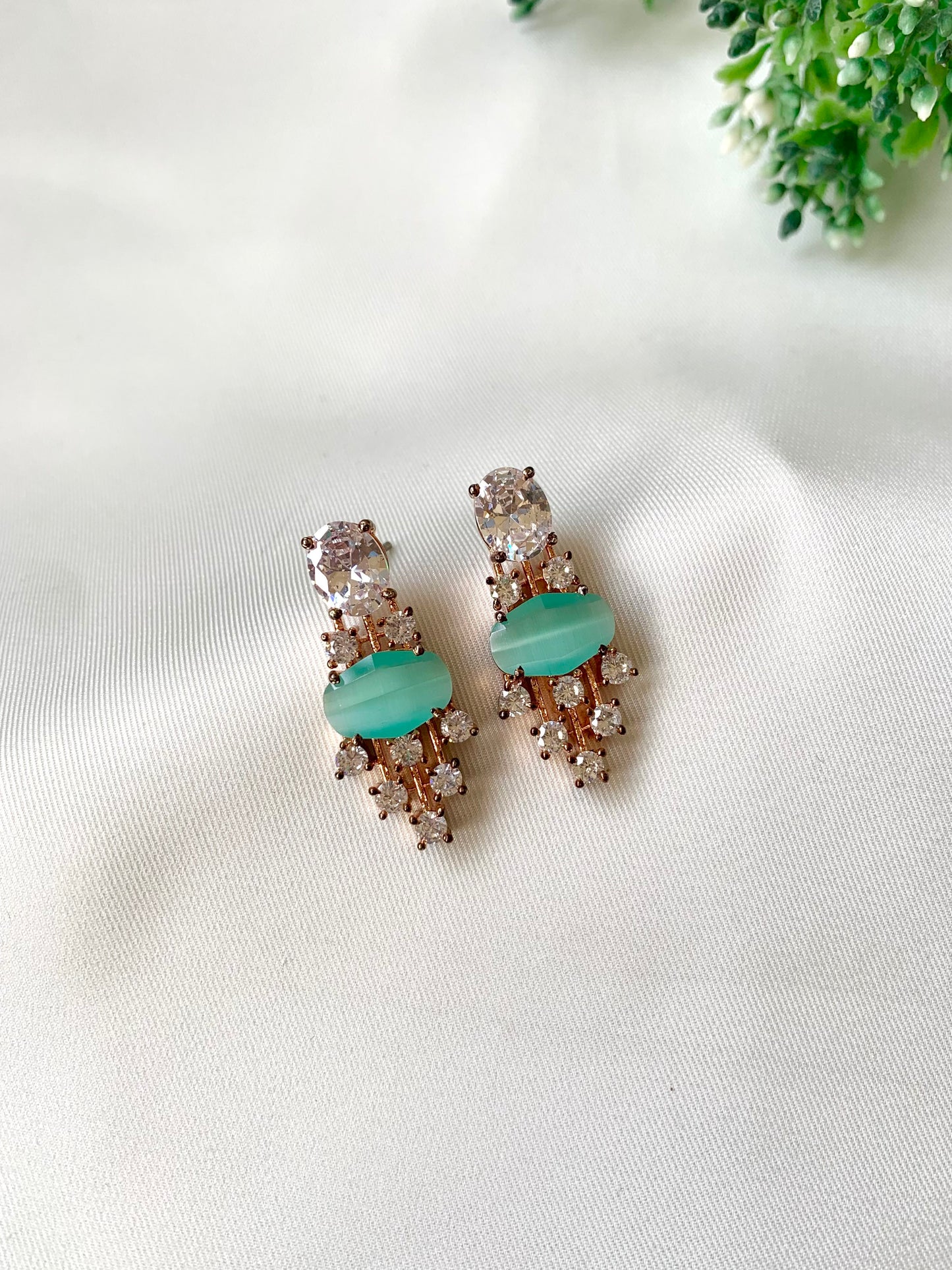 Pair of earrings with turquoise stones on a white fabric background