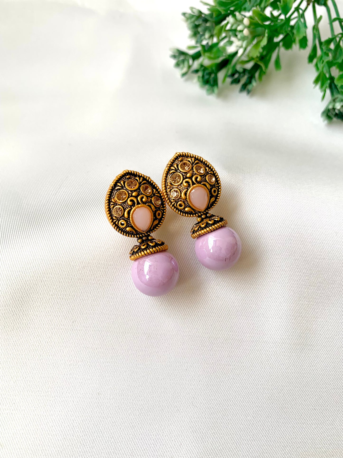 Pair of earrings with purple and gold designs on a white background