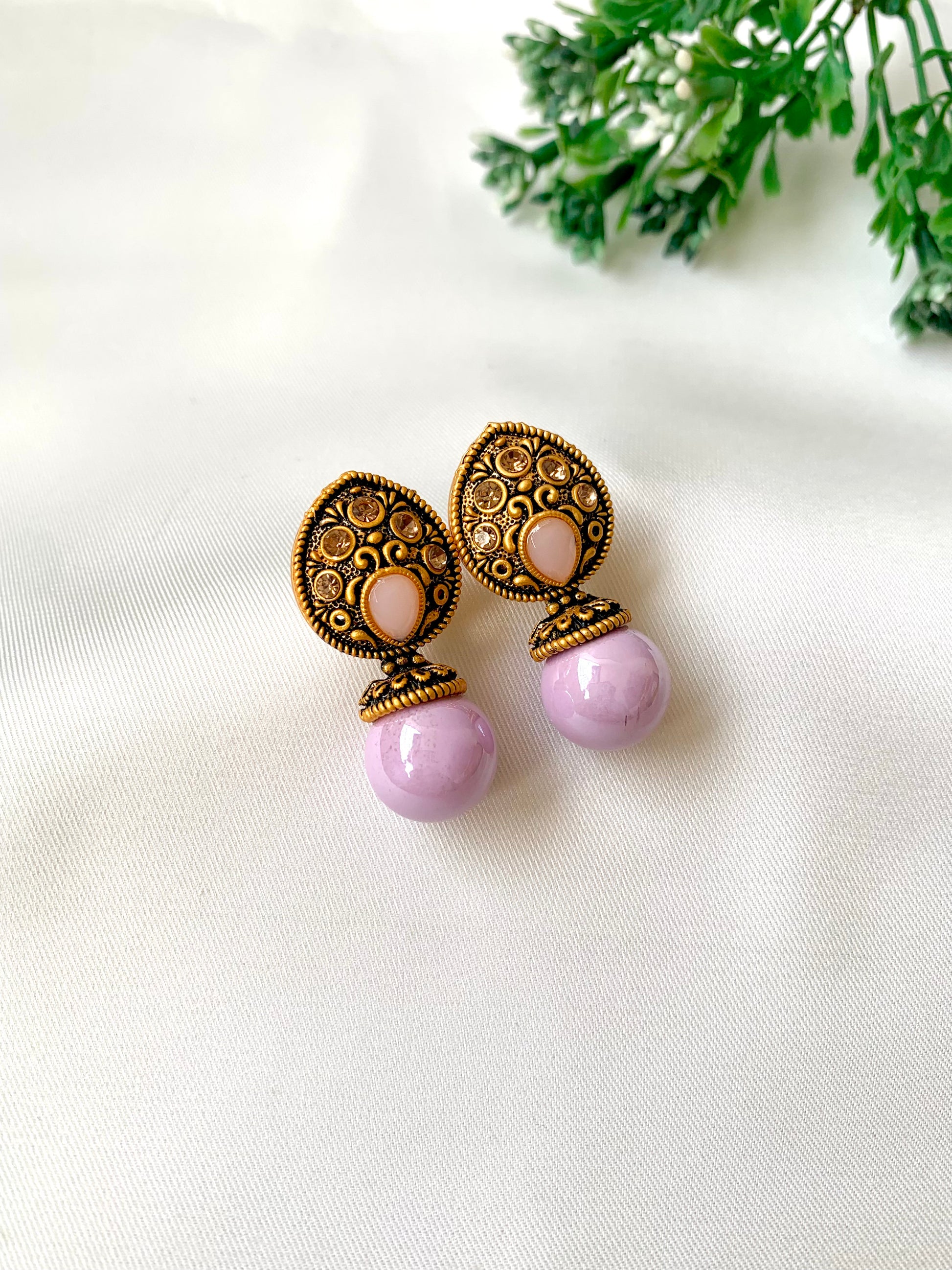 Pair of earrings with purple and gold designs on a white background