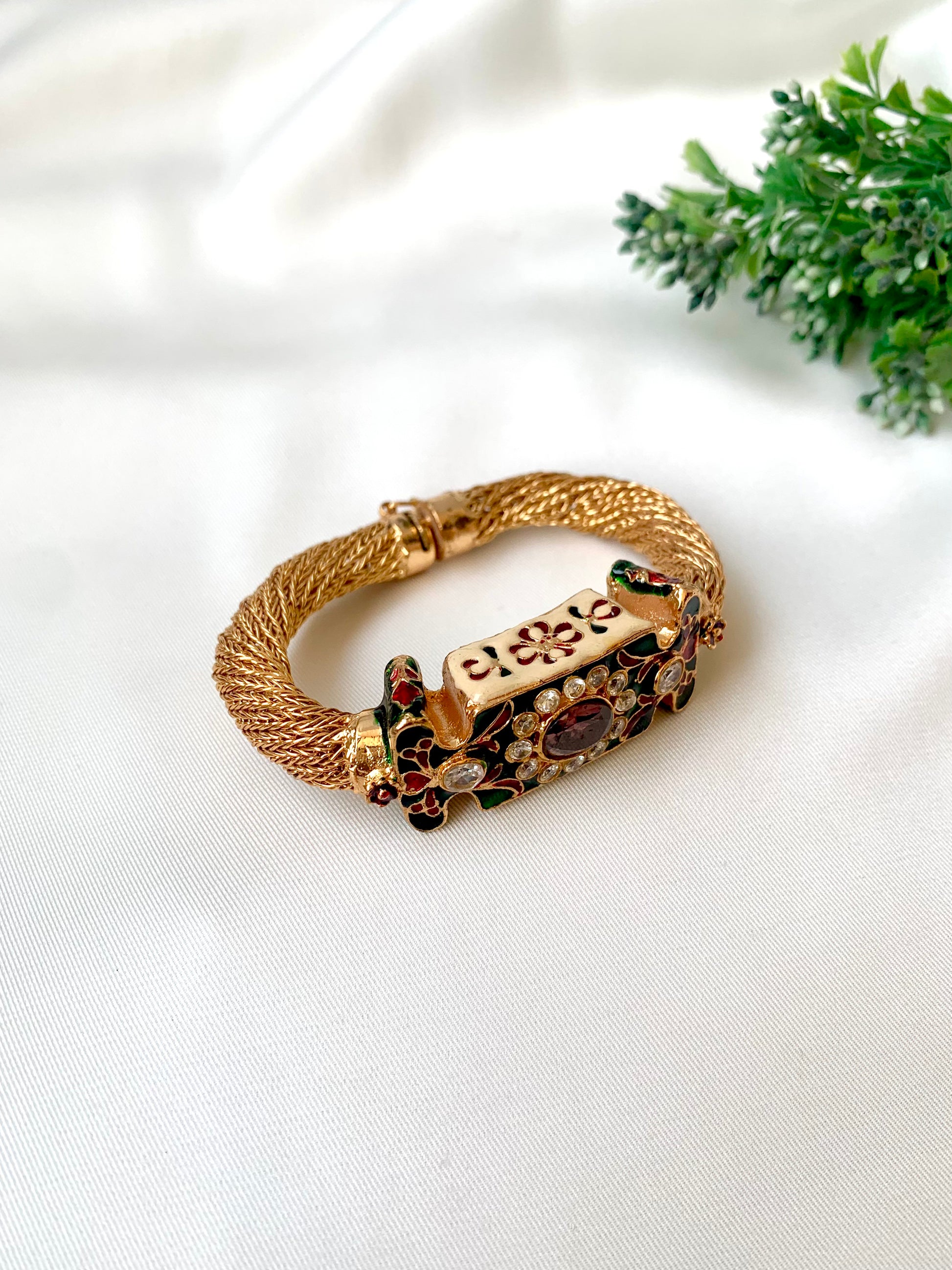 Gold bracelet with gemstones on a white fabric background