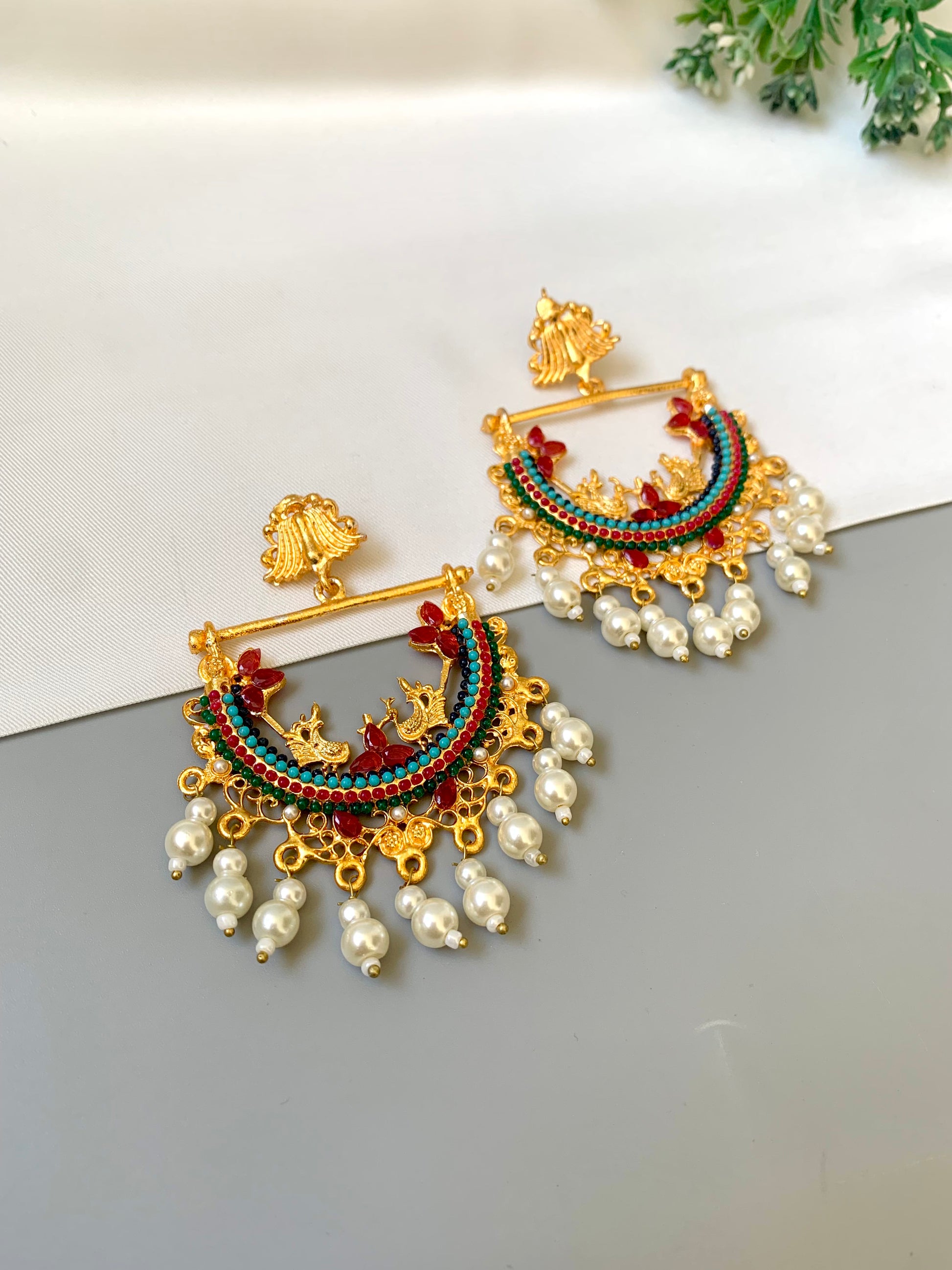 Ornate earrings with pearls on a light background