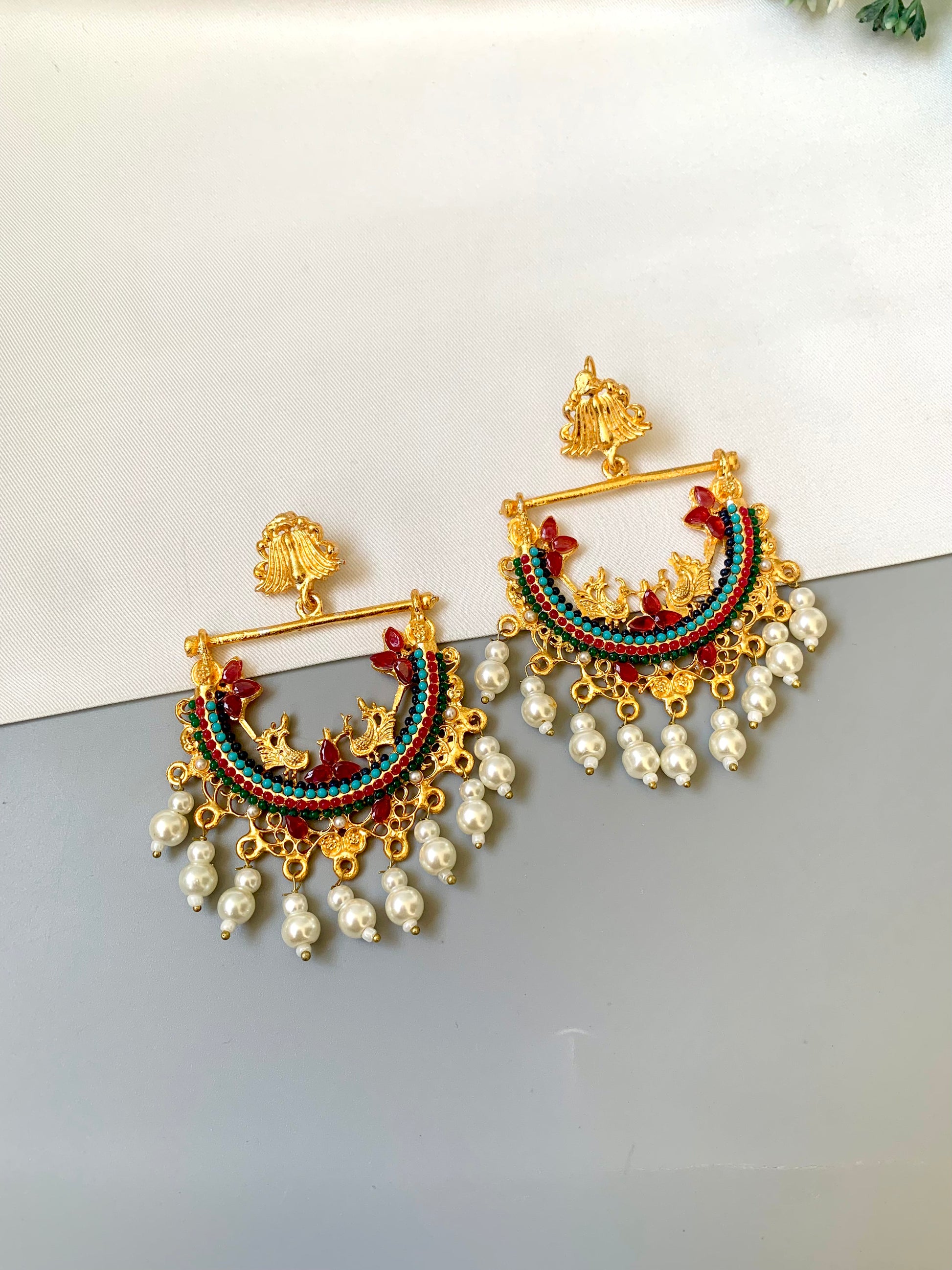 Ornate earrings with pearls on a light gray background