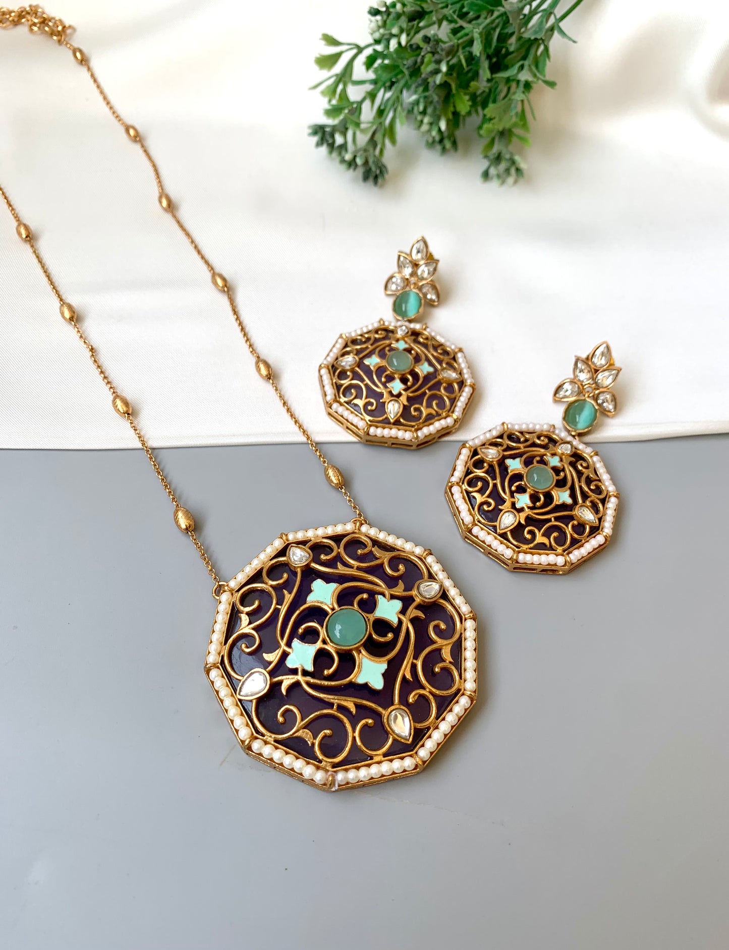 Ornate necklace and earrings with turquoise stones on a light background