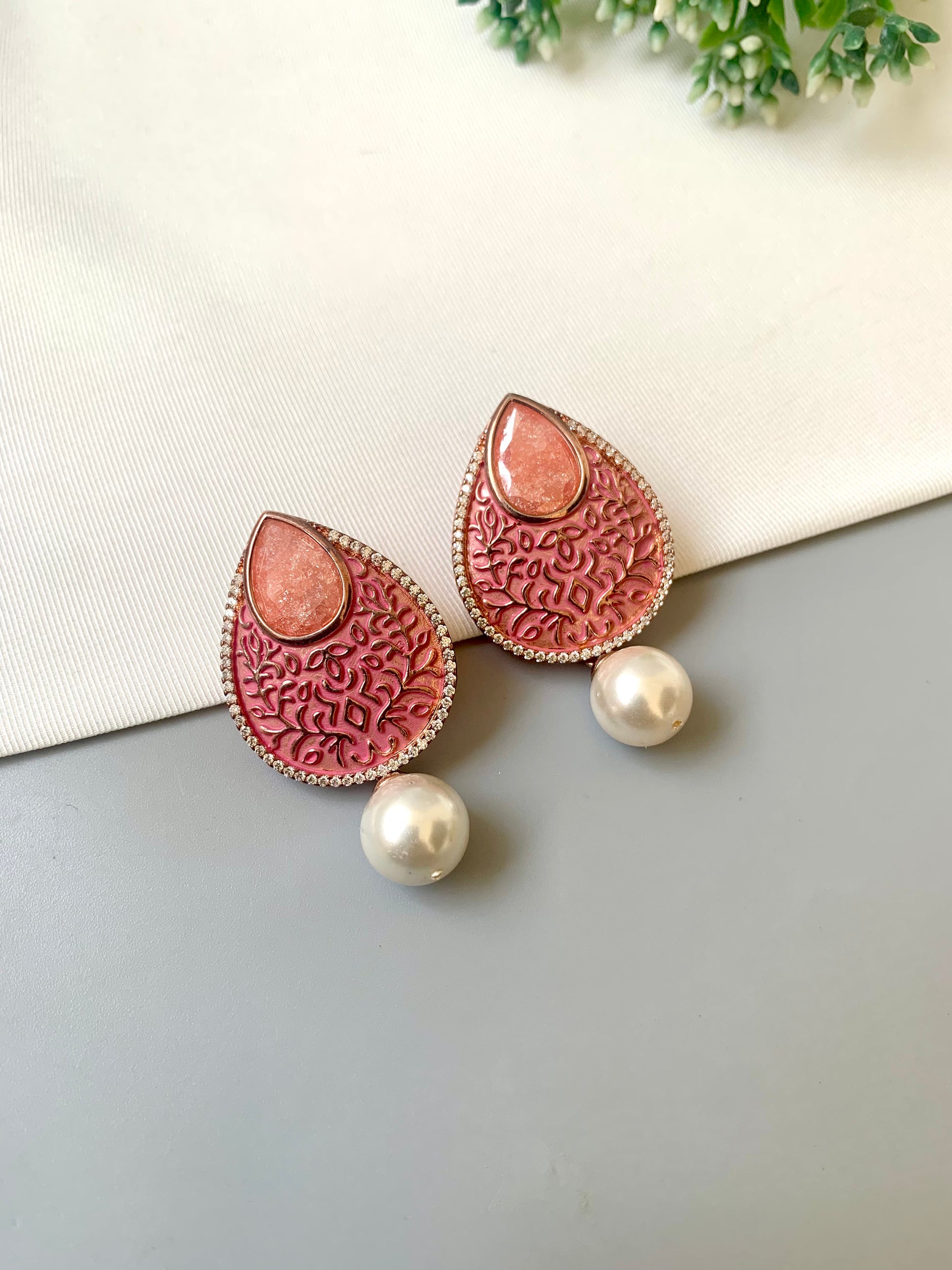 Pink earrings with pearl accents on a light gray surface