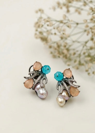 Pair of earrings with pearls and gemstones on a light background