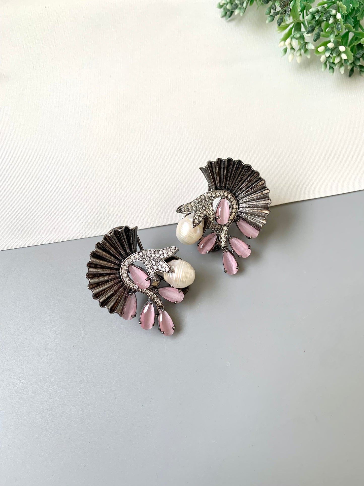 Pair of earrings with pink and pearl details on a light surface.