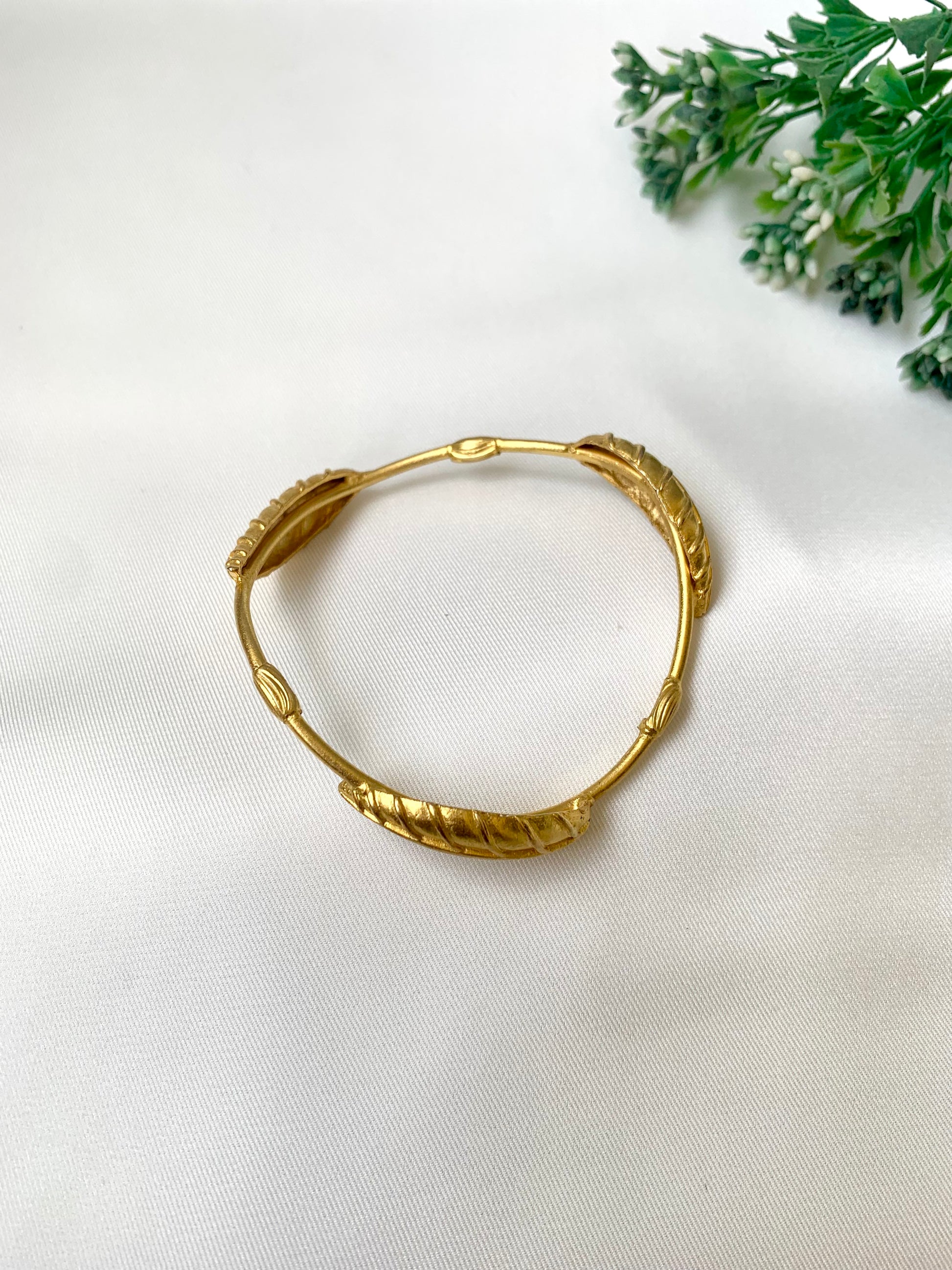 Rishani geometric gold bangle in curved triangular shape with hand carved leaf design