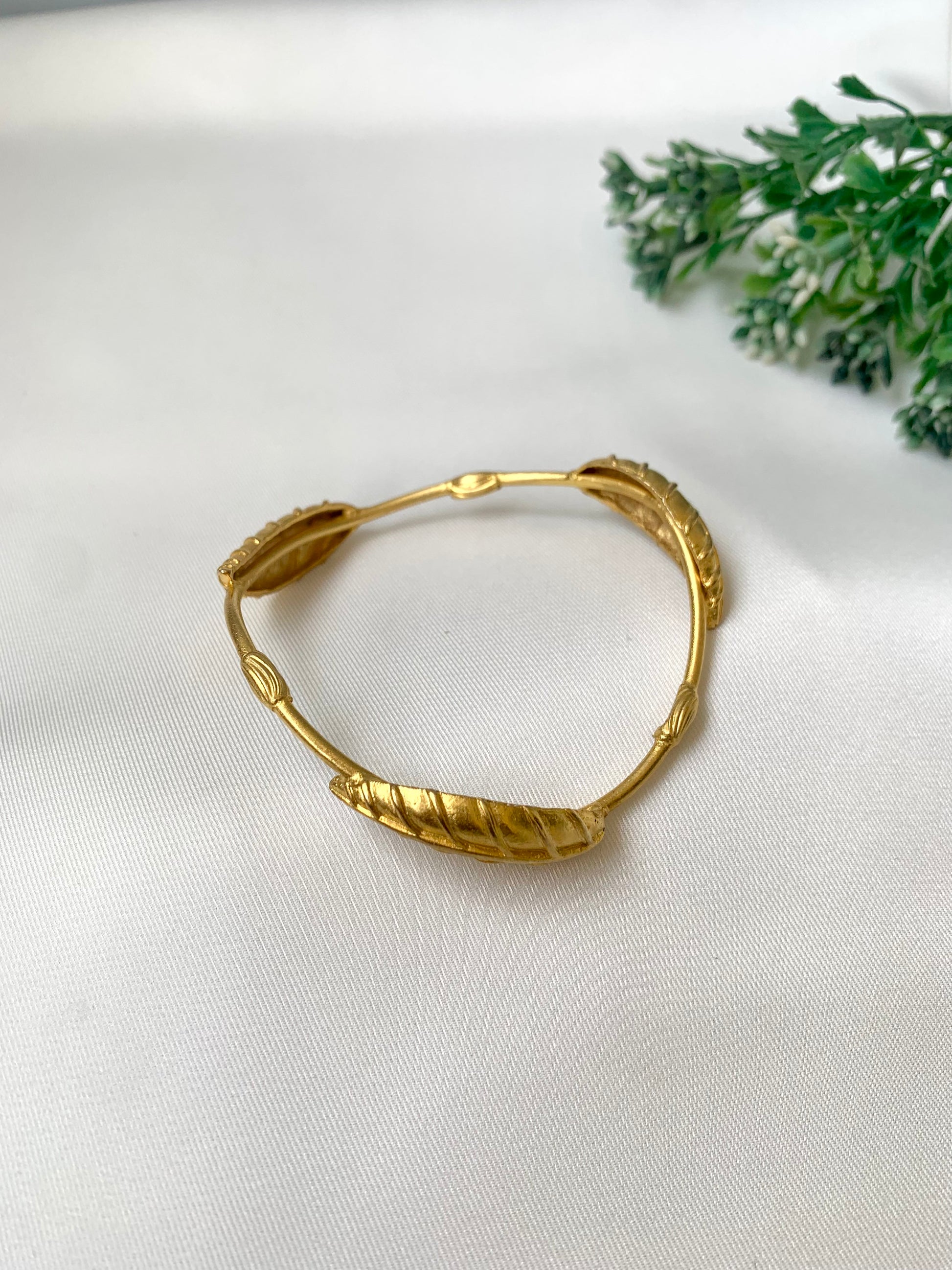 Rishani geometric gold bangle in curved triangular shape with hand carved leaf design