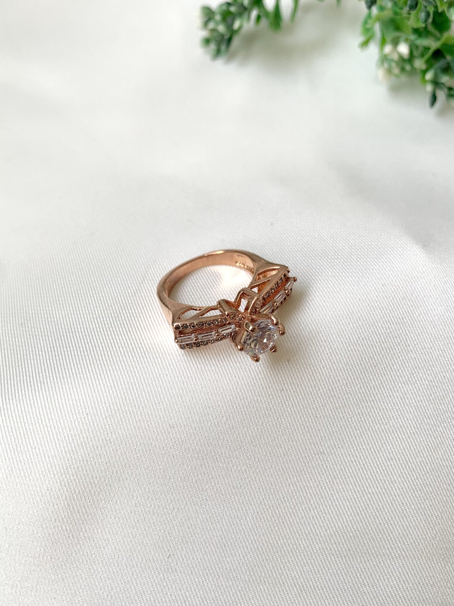 Rose gold ring with a large diamond on a white fabric background