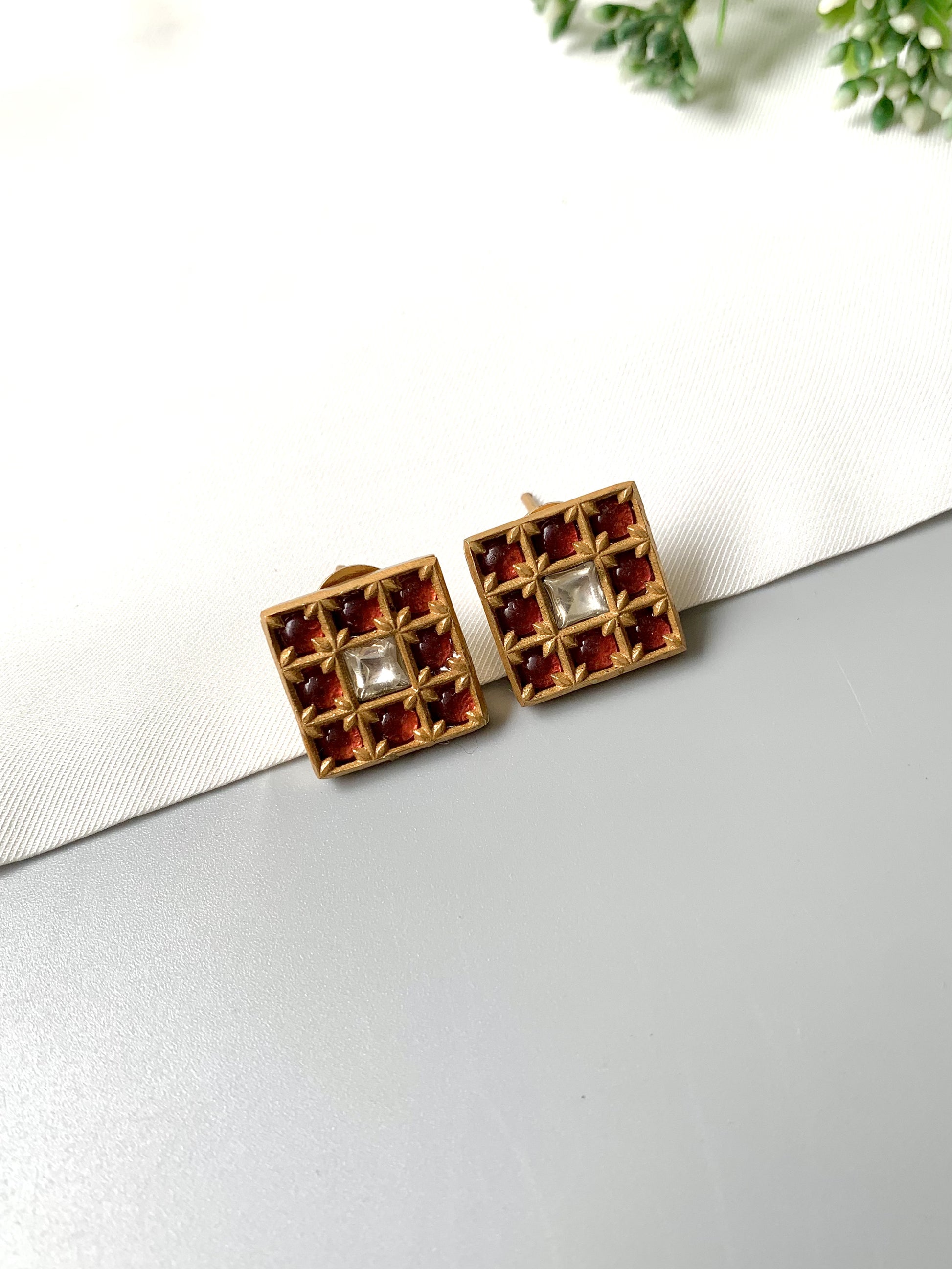 Zamal Jewels ruby grid Polki Kundan studs displayed flat with floral prop