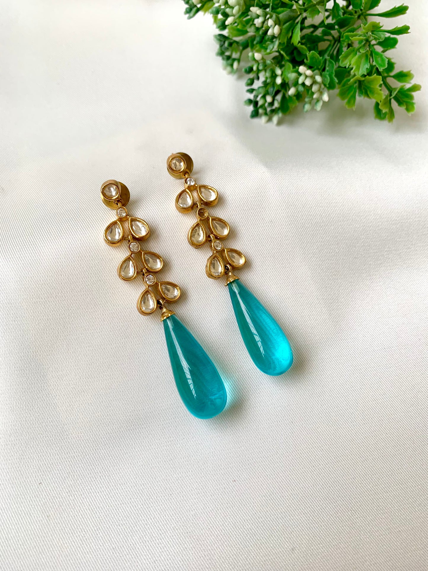 Turquoise teardrop earrings with gold accents on a white background