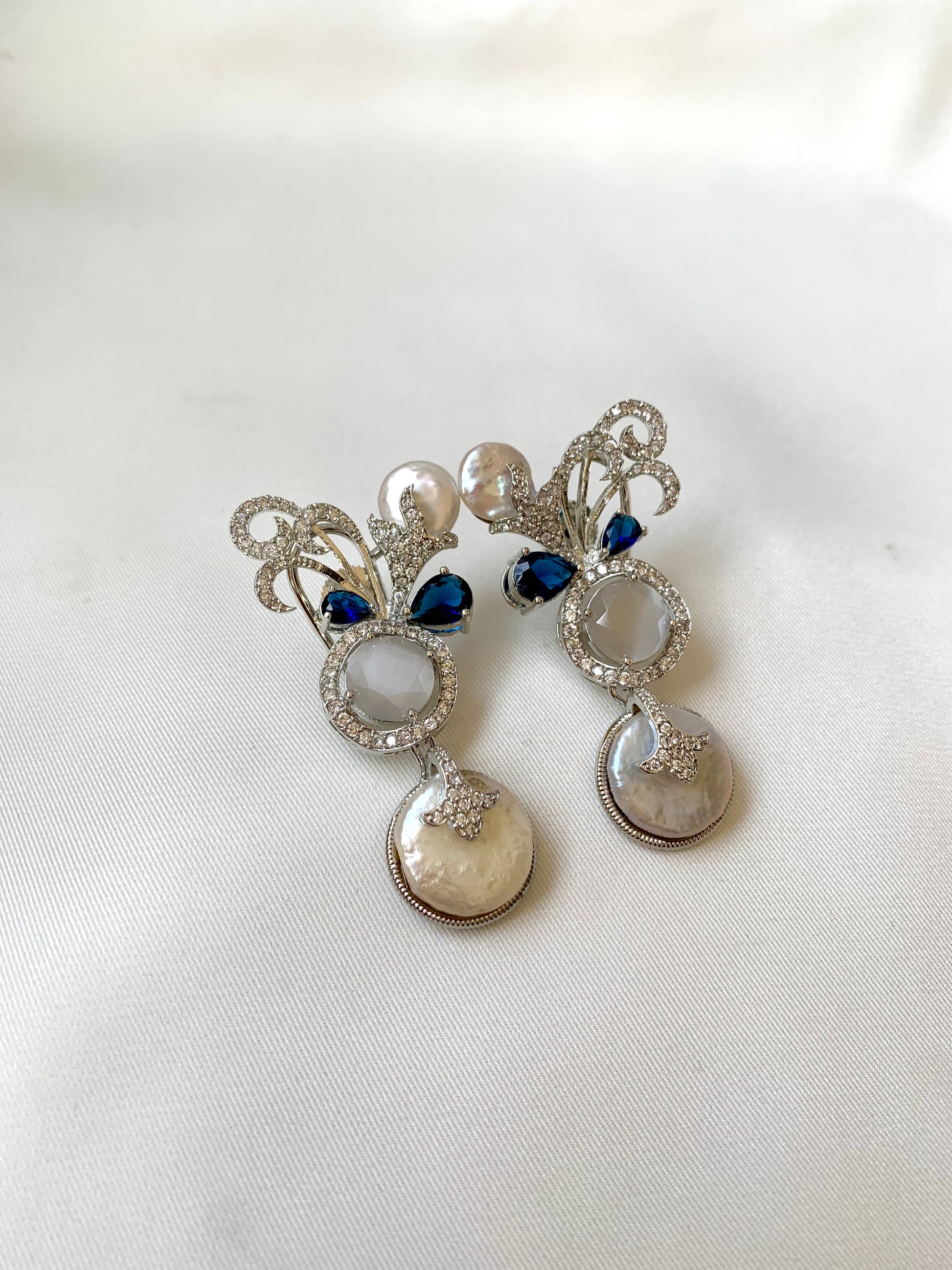Silver earrings with blue gemstones on a white fabric background