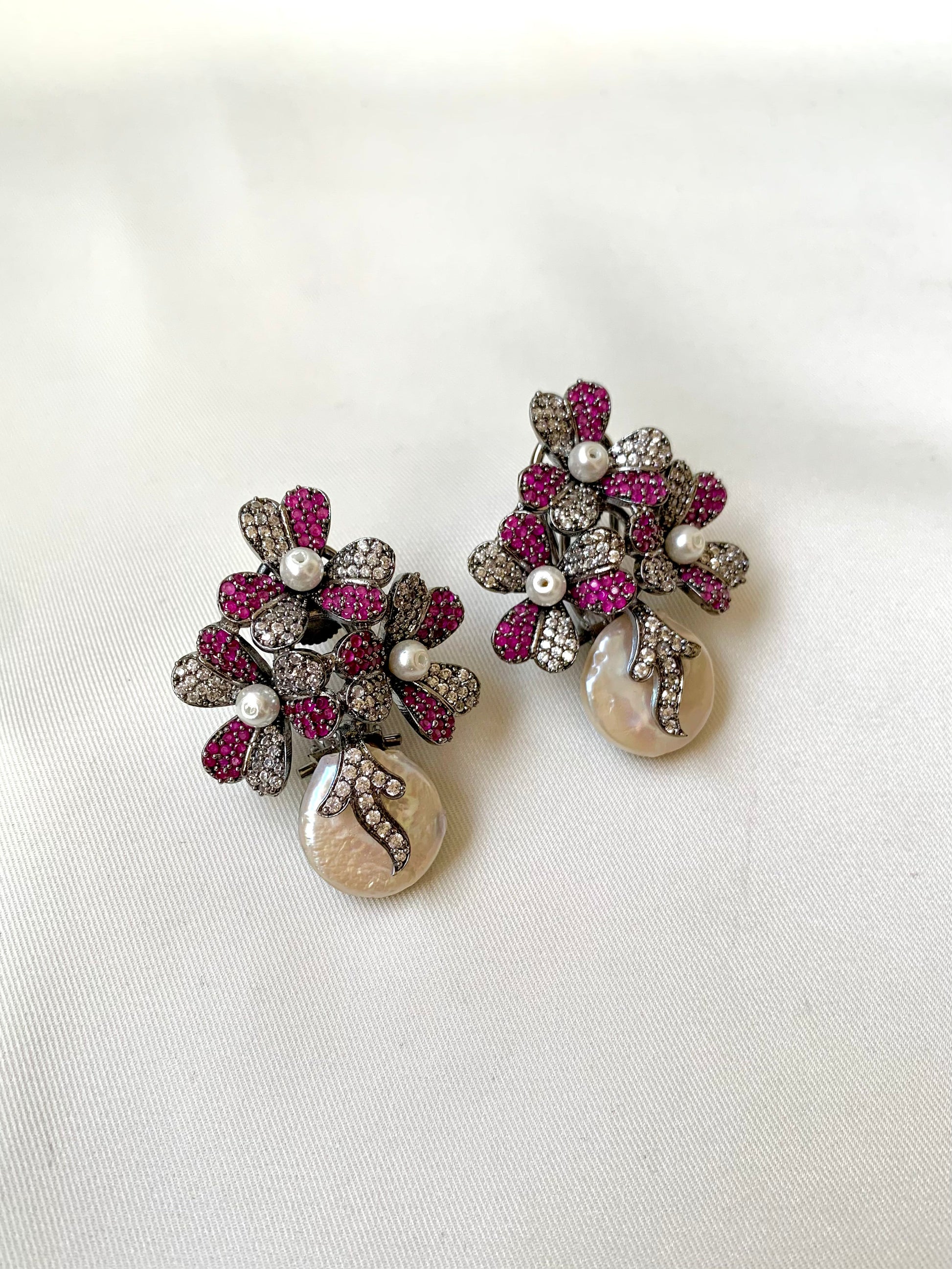 Pair of earrings with floral design and pearl-like beads on a white background