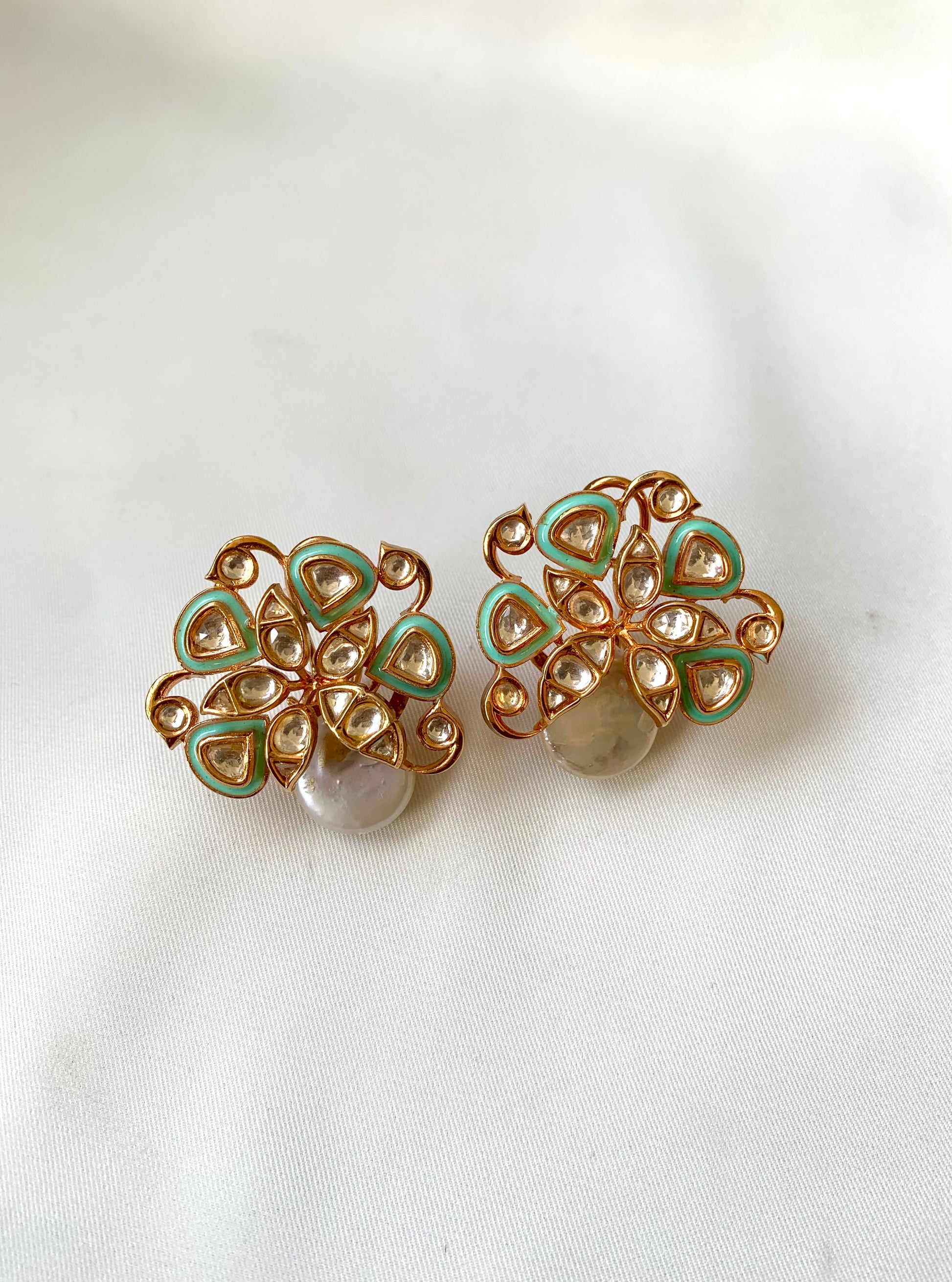Pair of gold and green floral earrings on a white background