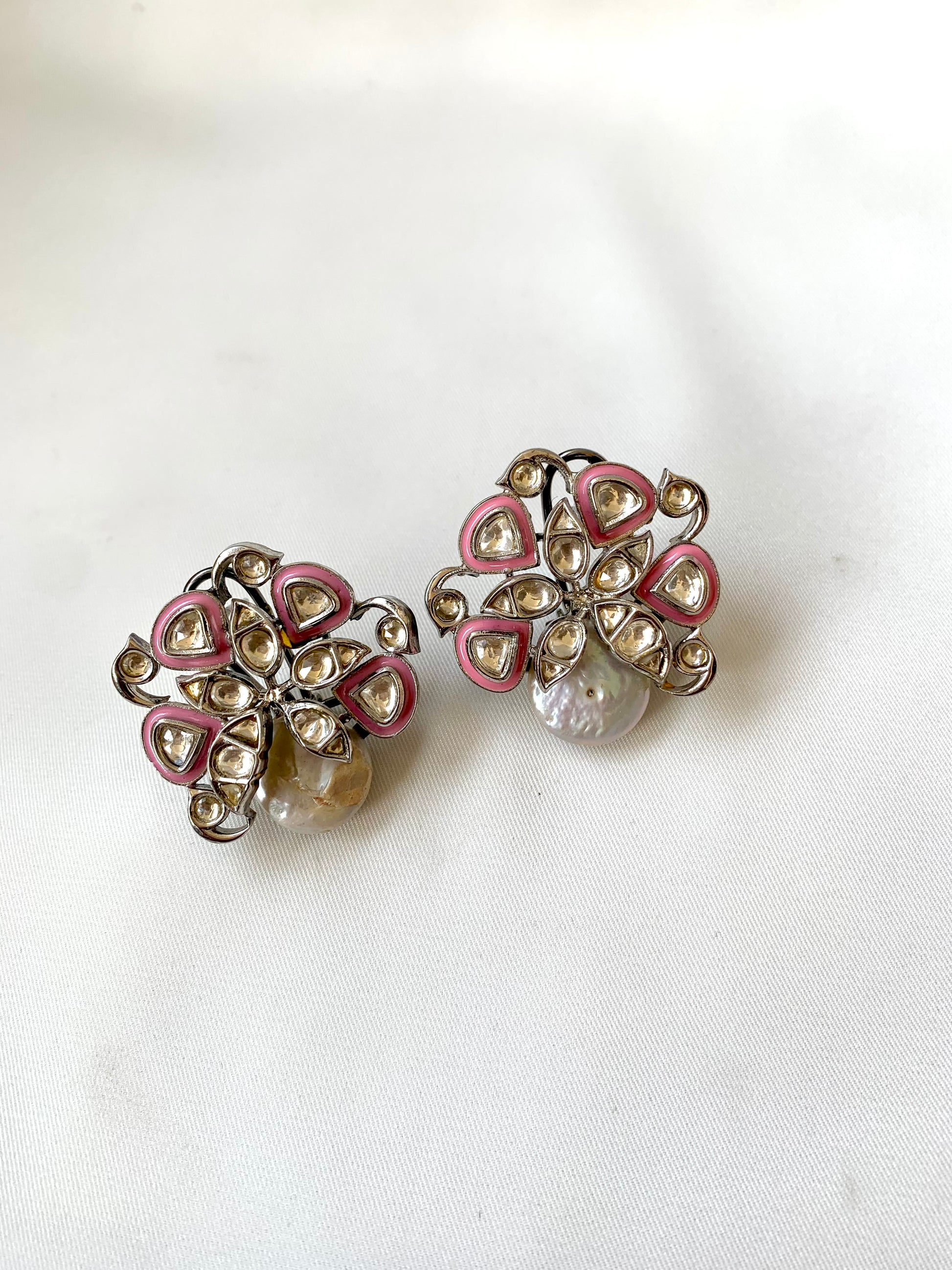 Pair of earrings with pink and clear gemstones on a white background