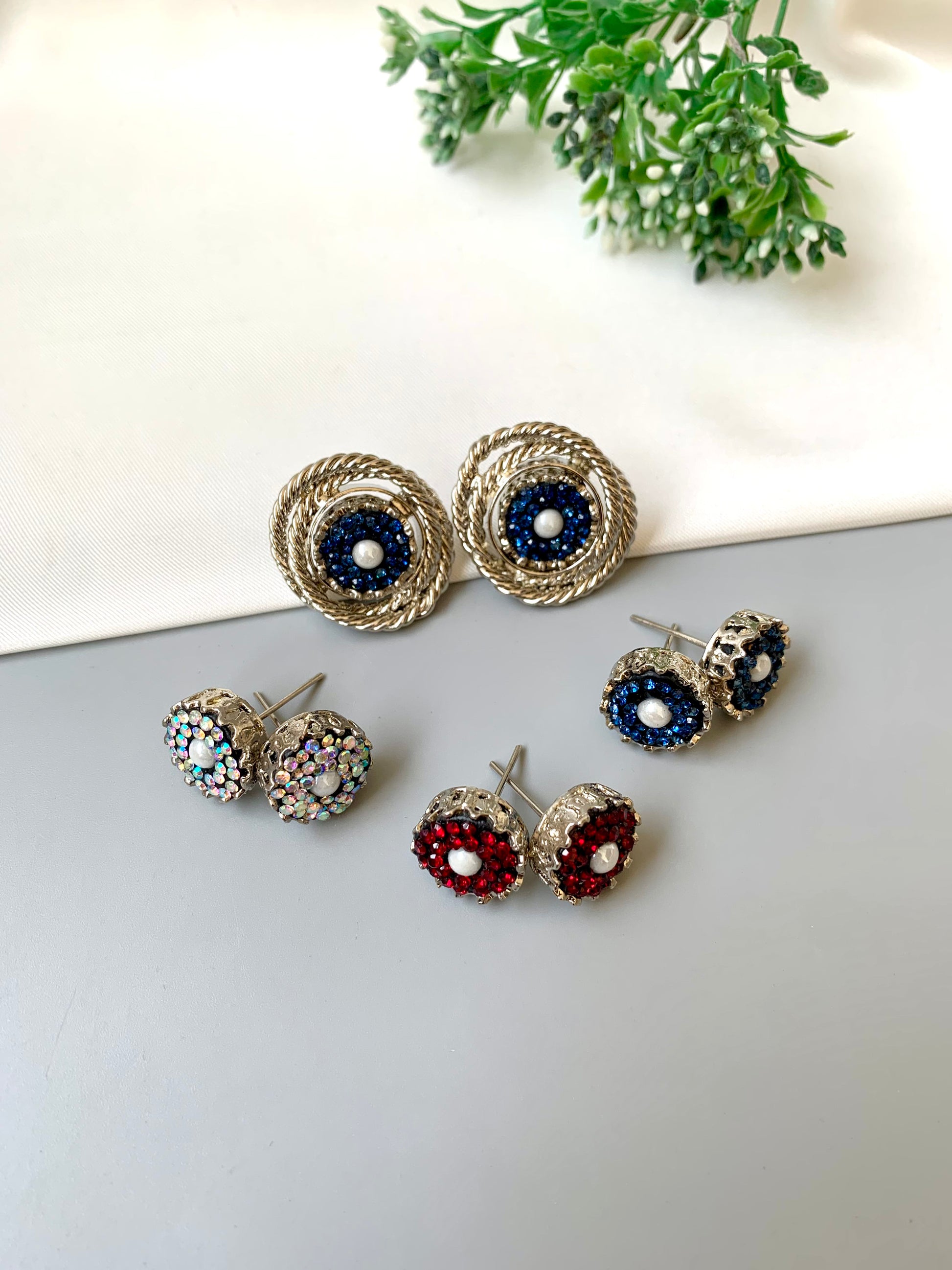 Set of silver earrings with blue and red gemstones on a white surface.