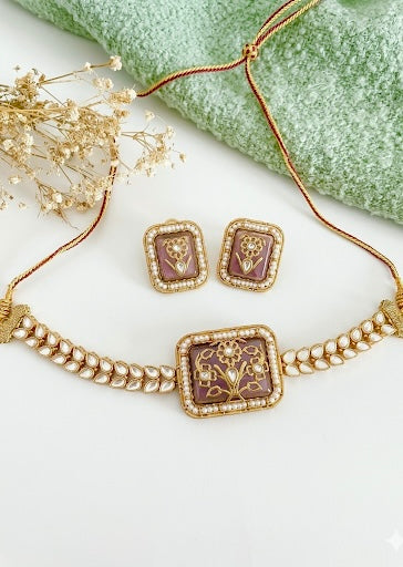 Gold necklace and earrings with intricate designs on a white surface.