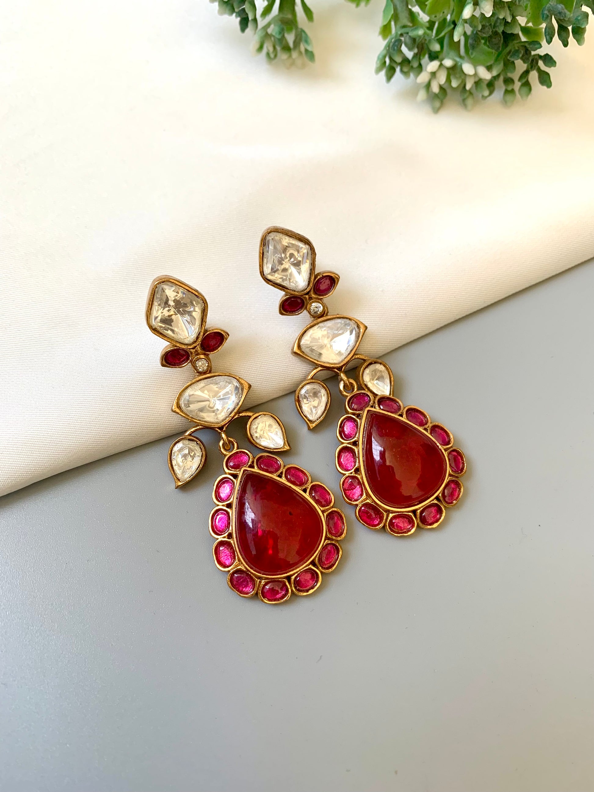 Ornate earrings with red gemstones on a light surface
