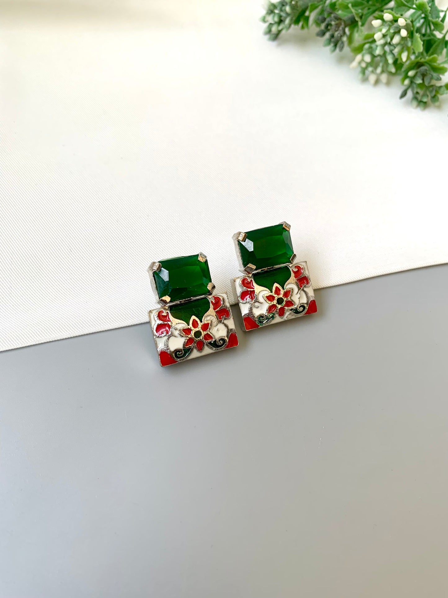 Pair of earrings with green gemstones on a white surface