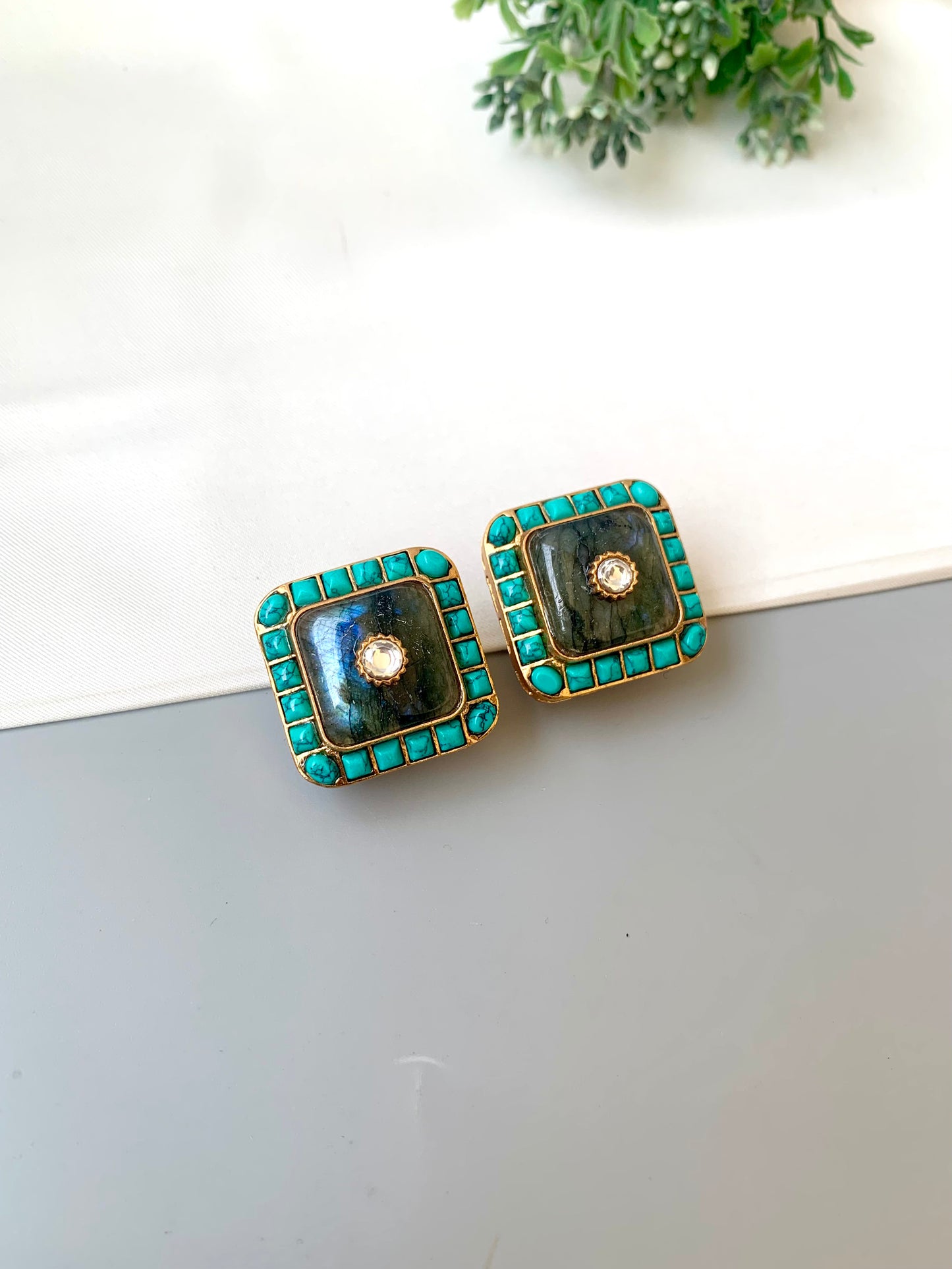 Pair of square earrings with green and gold accents on a white surface.