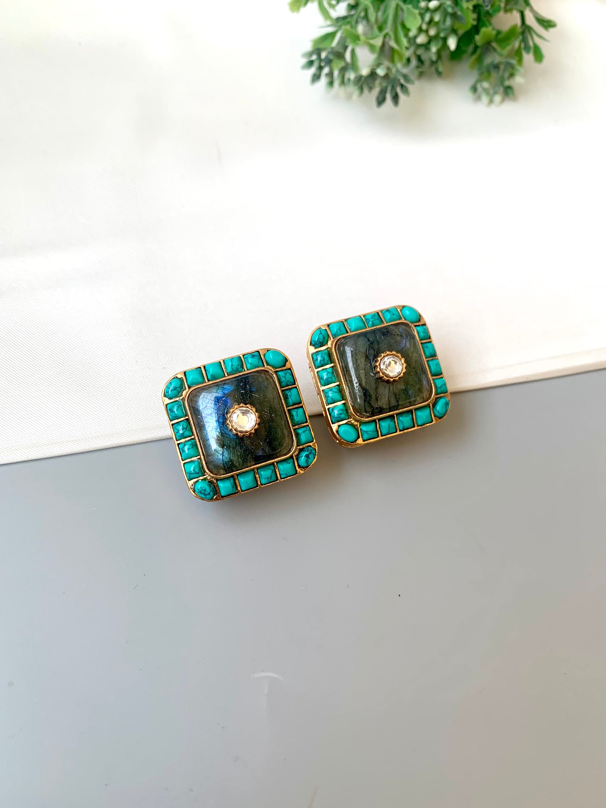 Pair of square earrings with green and gold accents on a white surface.