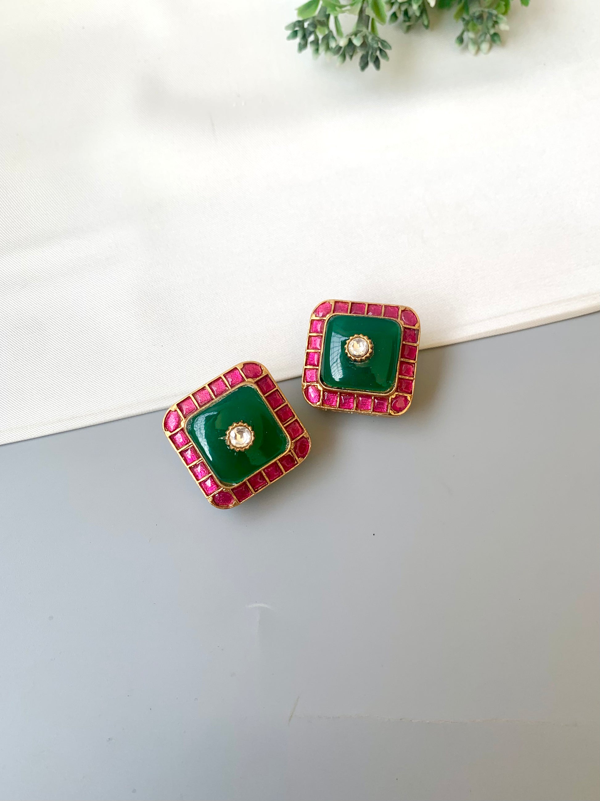 Green square earrings with red border on a white surface