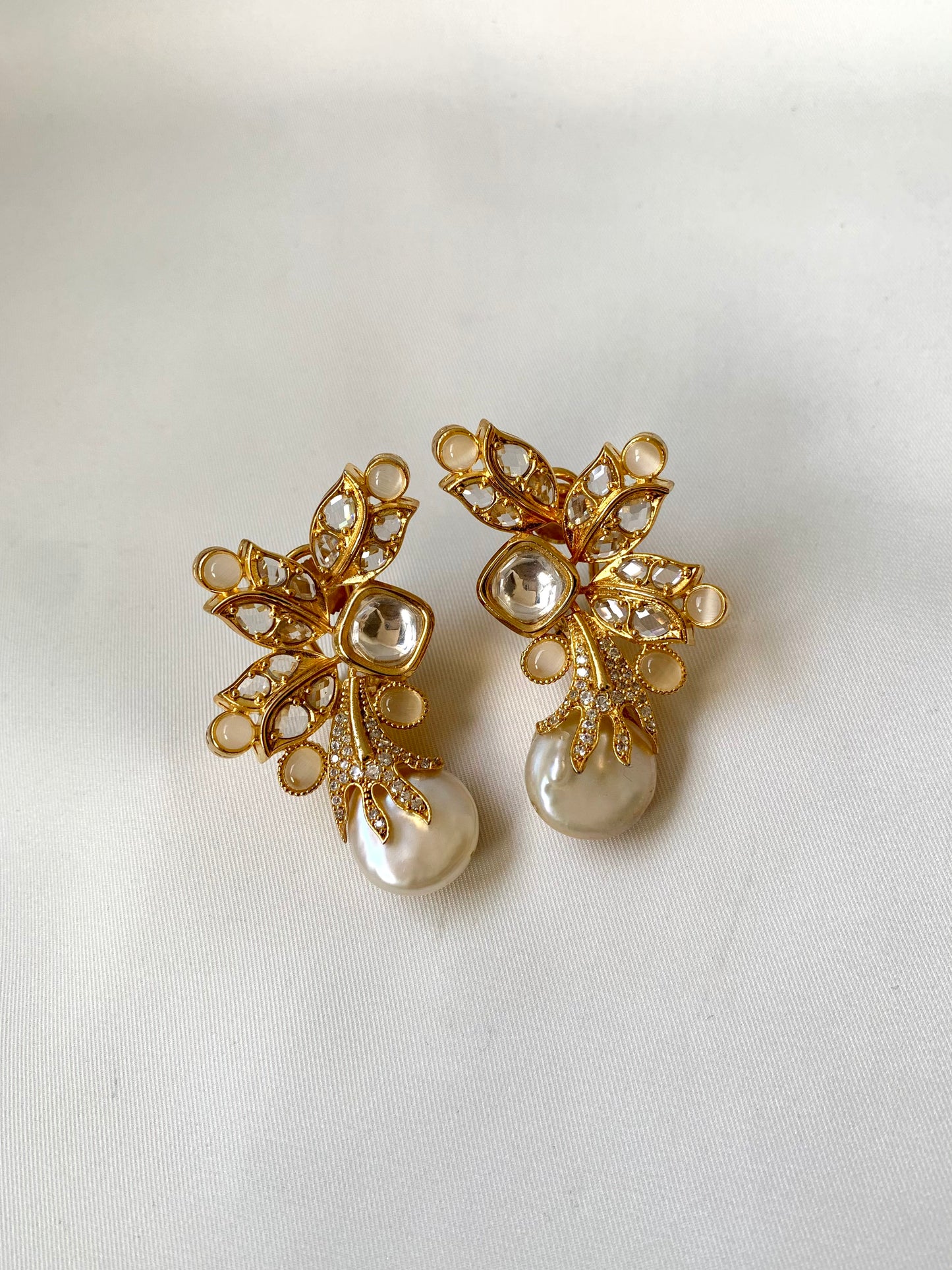 Gold and pearl earrings on a white background